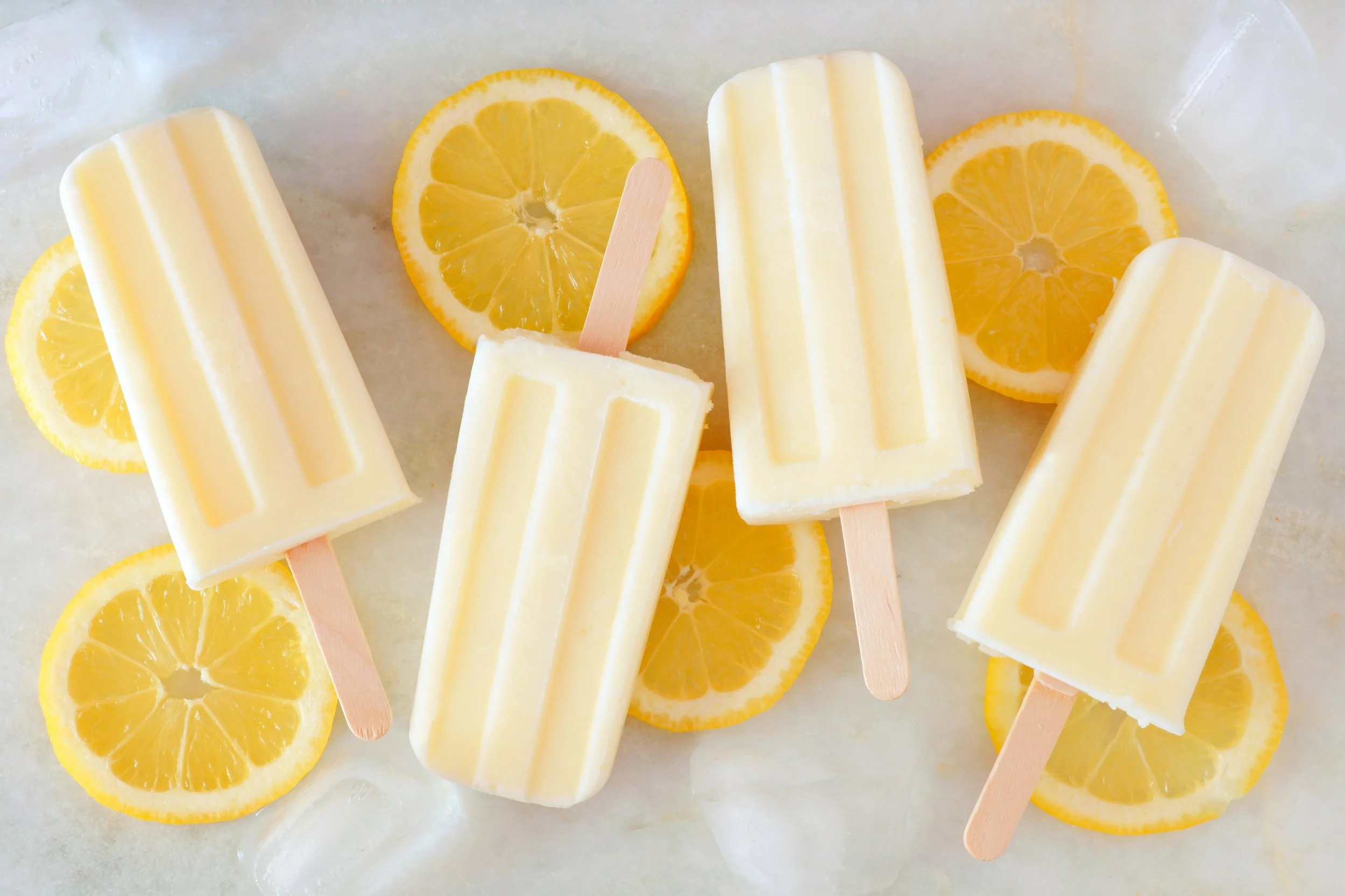 Stock photo of yellow popsicles lying on lemon slices.