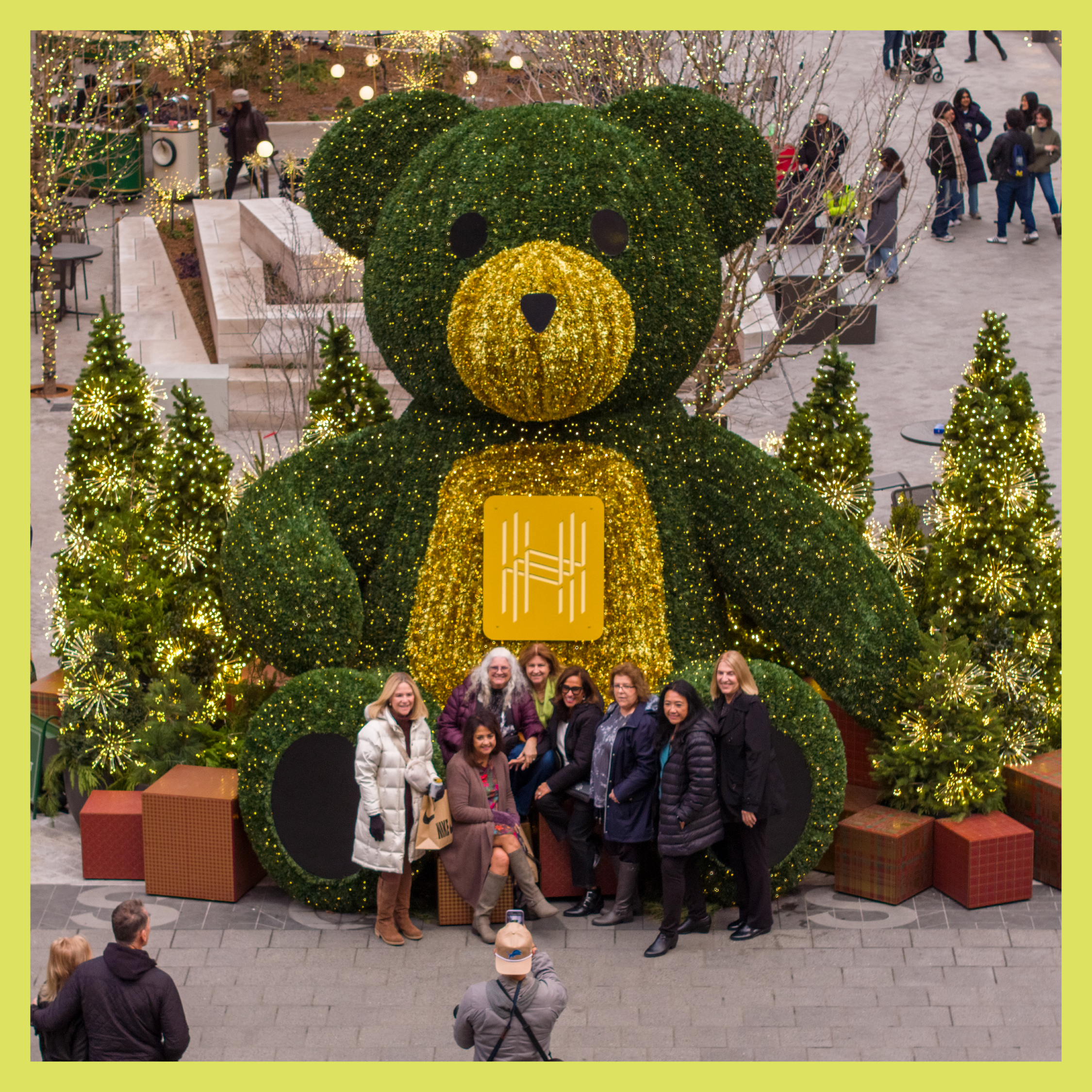 Group of people taking a photo in front of the Hudson's Bear large-scale display at Nick Gilbert Way in downtown Detroit.