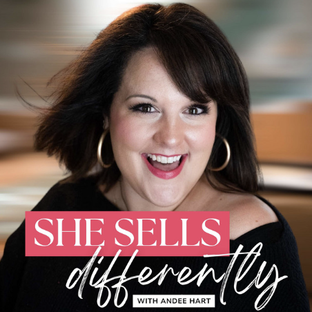 Close-up of a woman with dark brown hair, wearing hoop earrings, smiling, with a blurred indoor background. Text overlay says 'She Sells Differently with Andee Hart'.