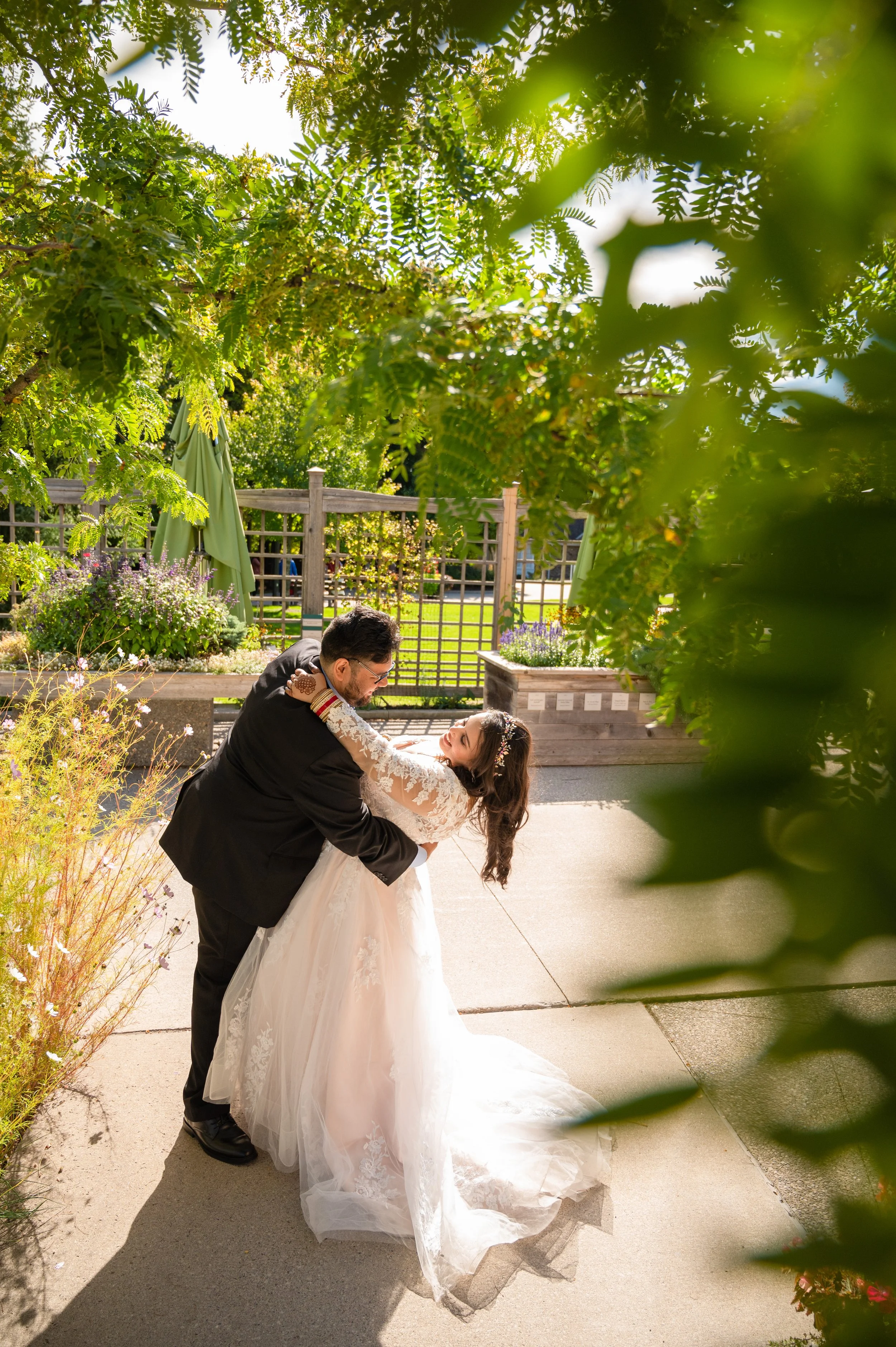 Groom dipping his bride during portraits surrounded by greenery at Riverwood Park Mississauga