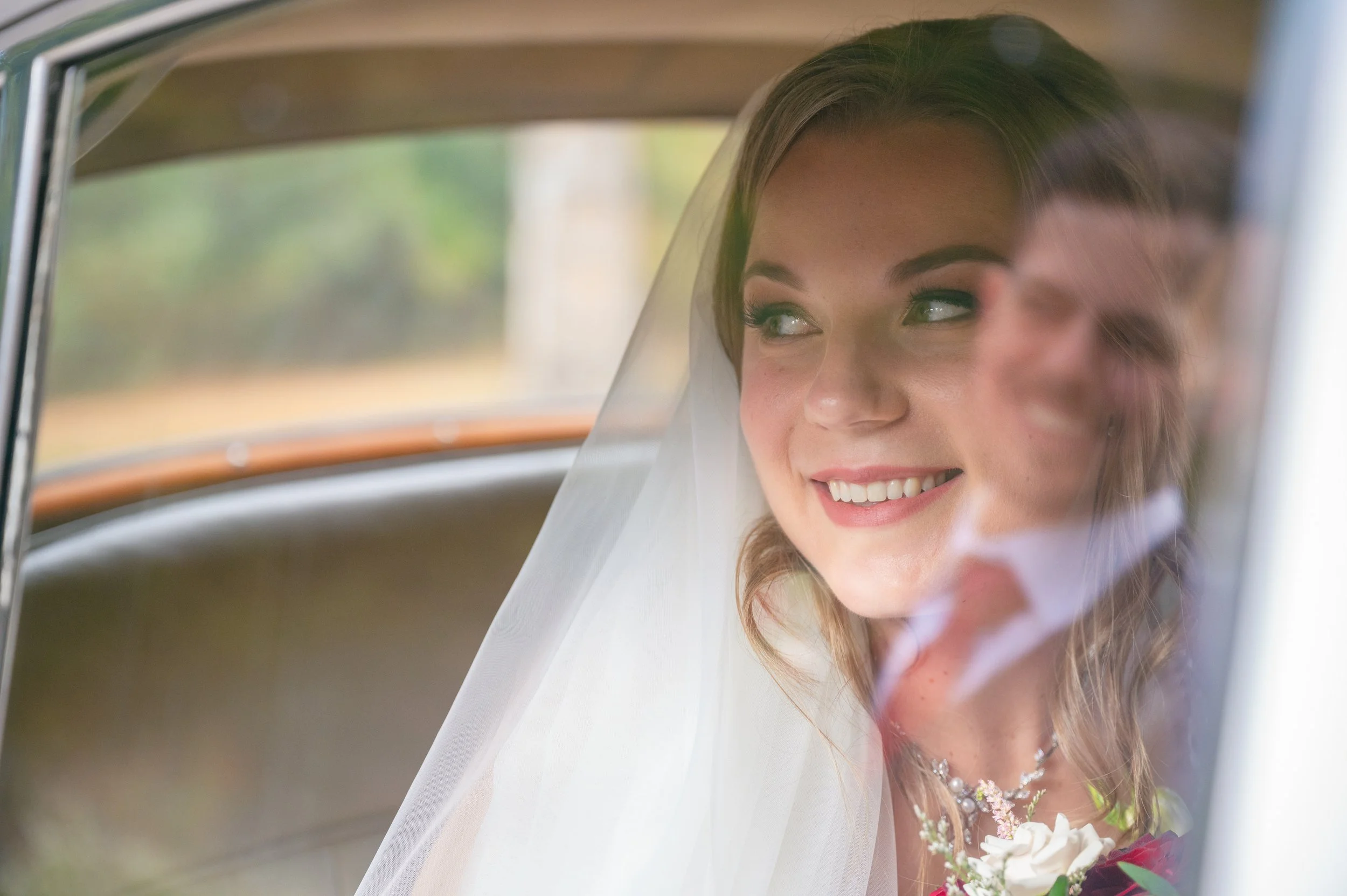 Bride looking out the window of a vintage car during her wedding portraits at Riverwood Park in Mississauga.