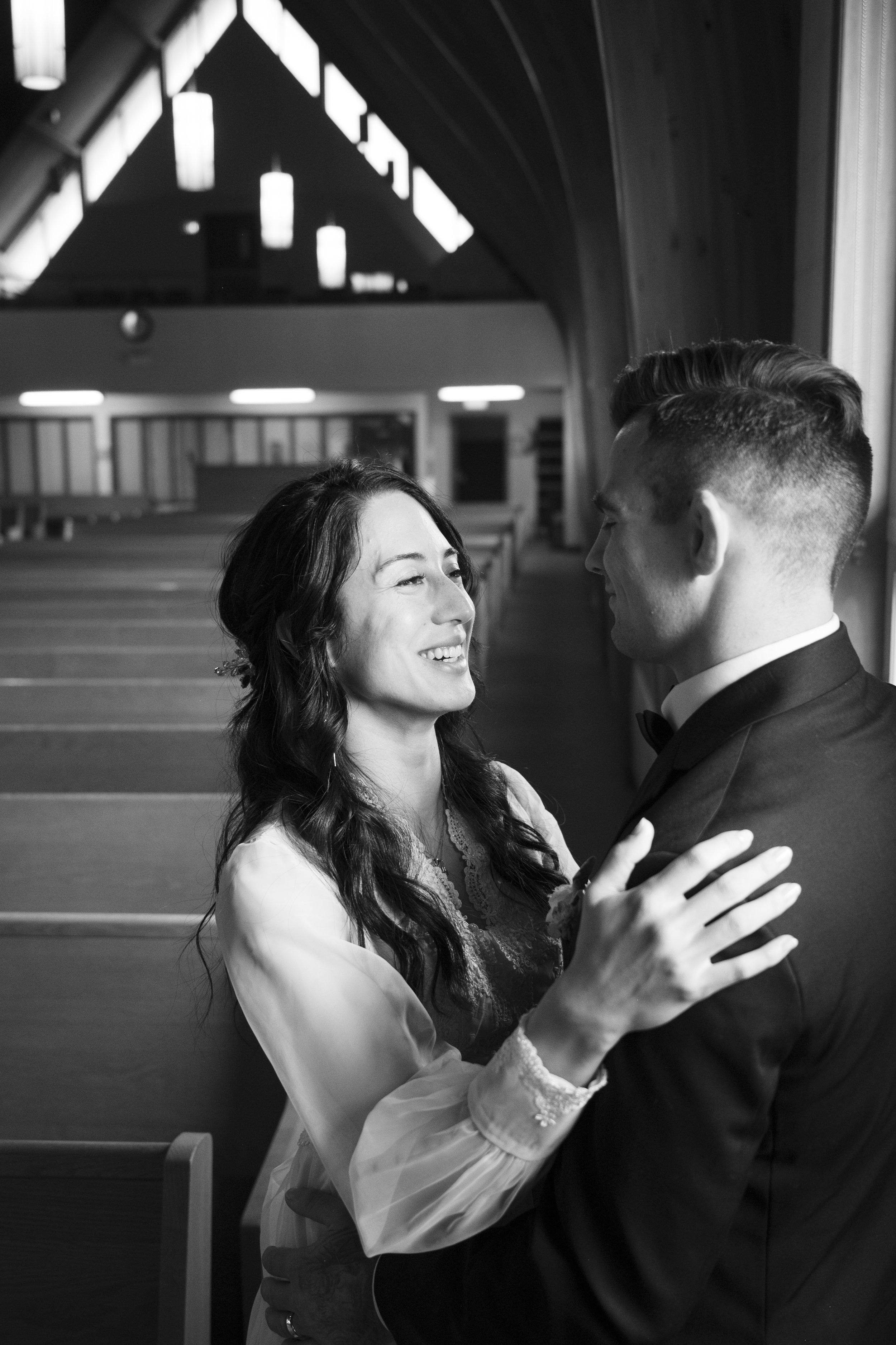 Bride smiling at her groom inside a softly lit church at Oakville, Ontario