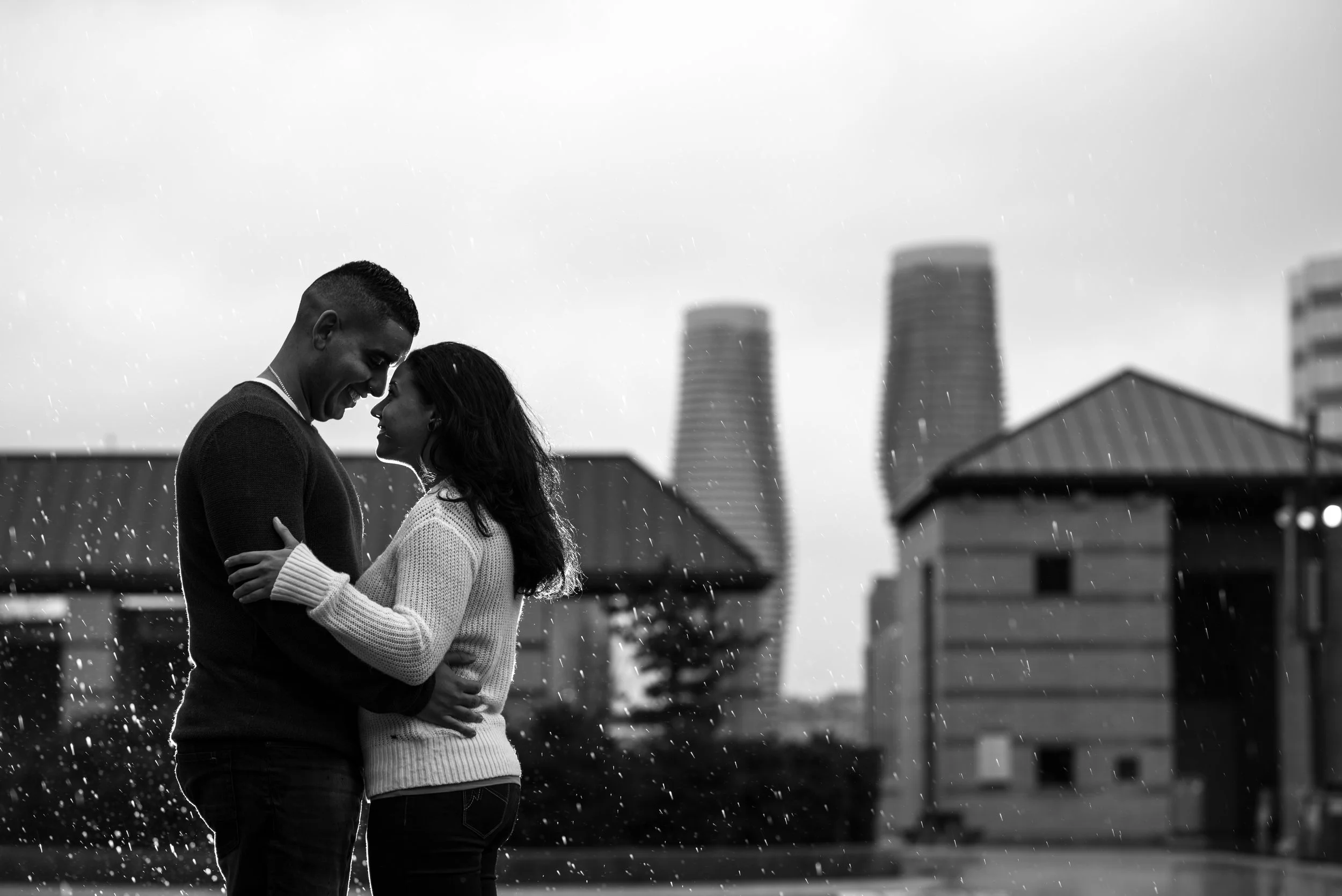 Couple holding each other in the rain at Celebration Square in Mississauga.