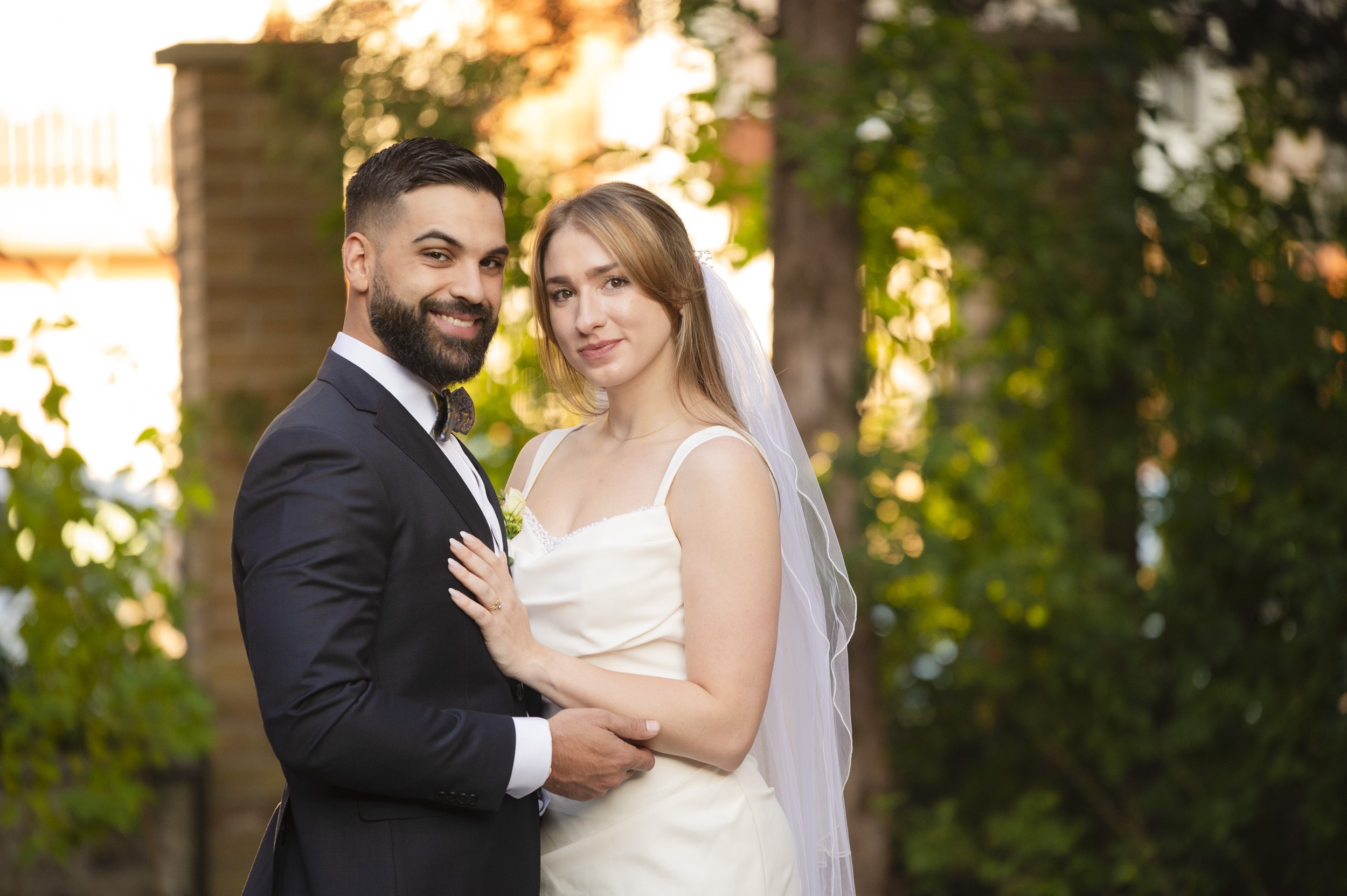 ride and groom smiling during golden hour portraits at Toronto based Church Garden