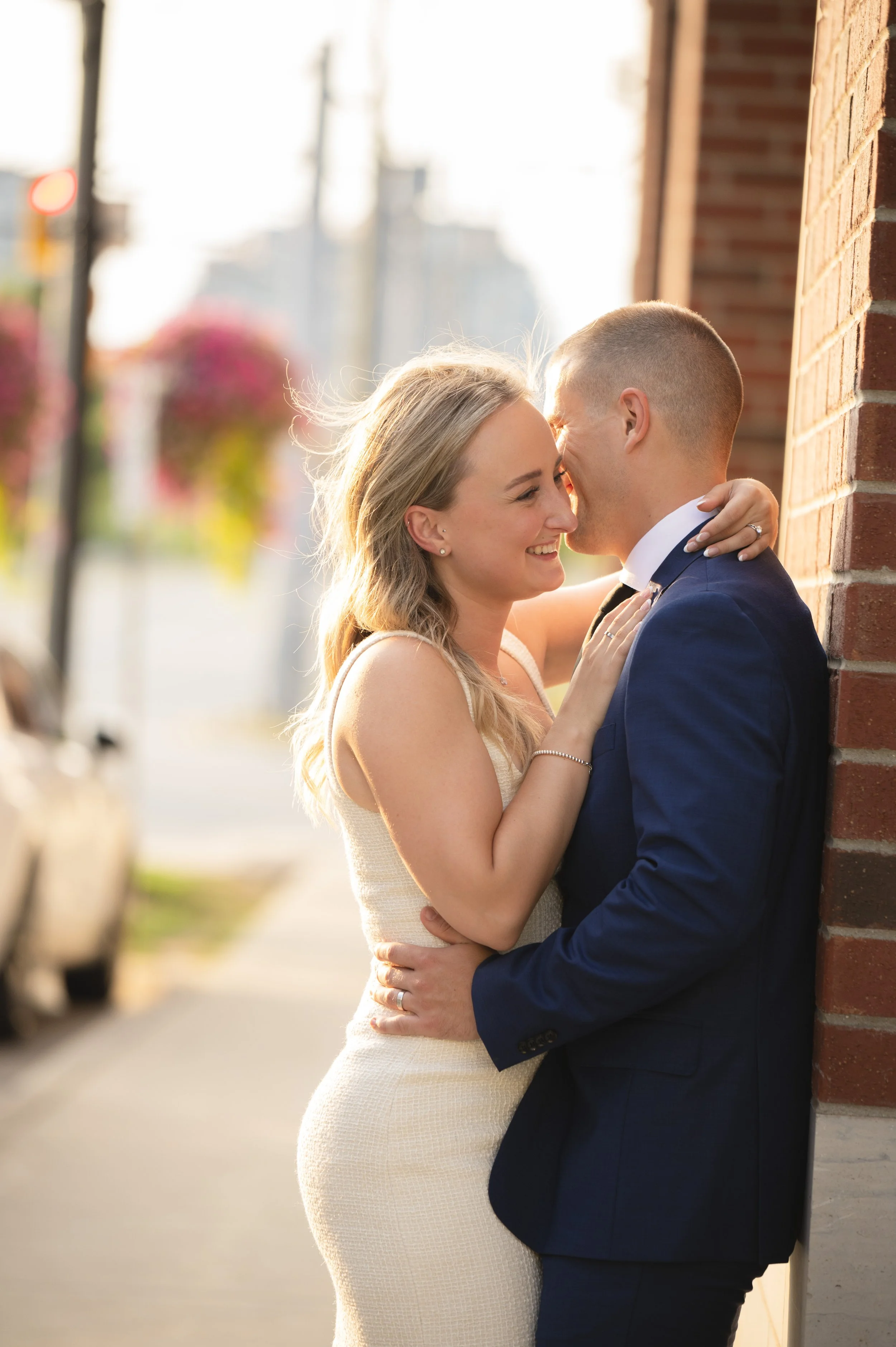 Couple holding each other on a city sidewalk at sunset at Downtown Waterloo