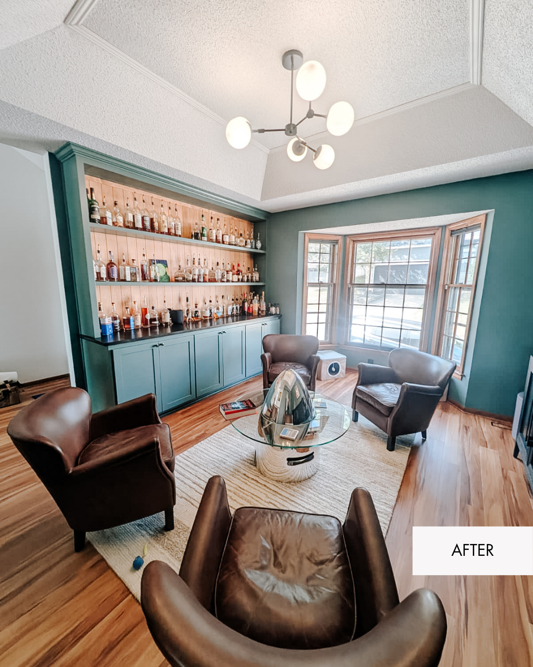 Remodeled front room turned bourbon room with custom bourbon cabinet, mid century modern light fixture and bourbon on display, sitting chairs and unique custom coffee table