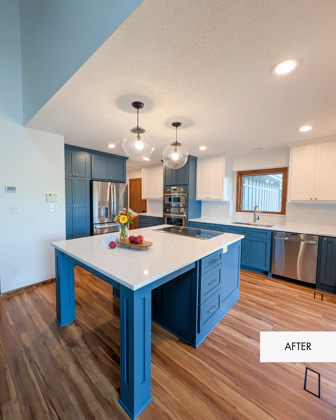 Remodeled Lee's Summit two toned kitchen with stainless steel appliances, warm wood tone lvp, white walls, white upper cabinetry, blue lower cabinetry, MSI Sparkling White quartz countertops, new flooring and an open living room connection