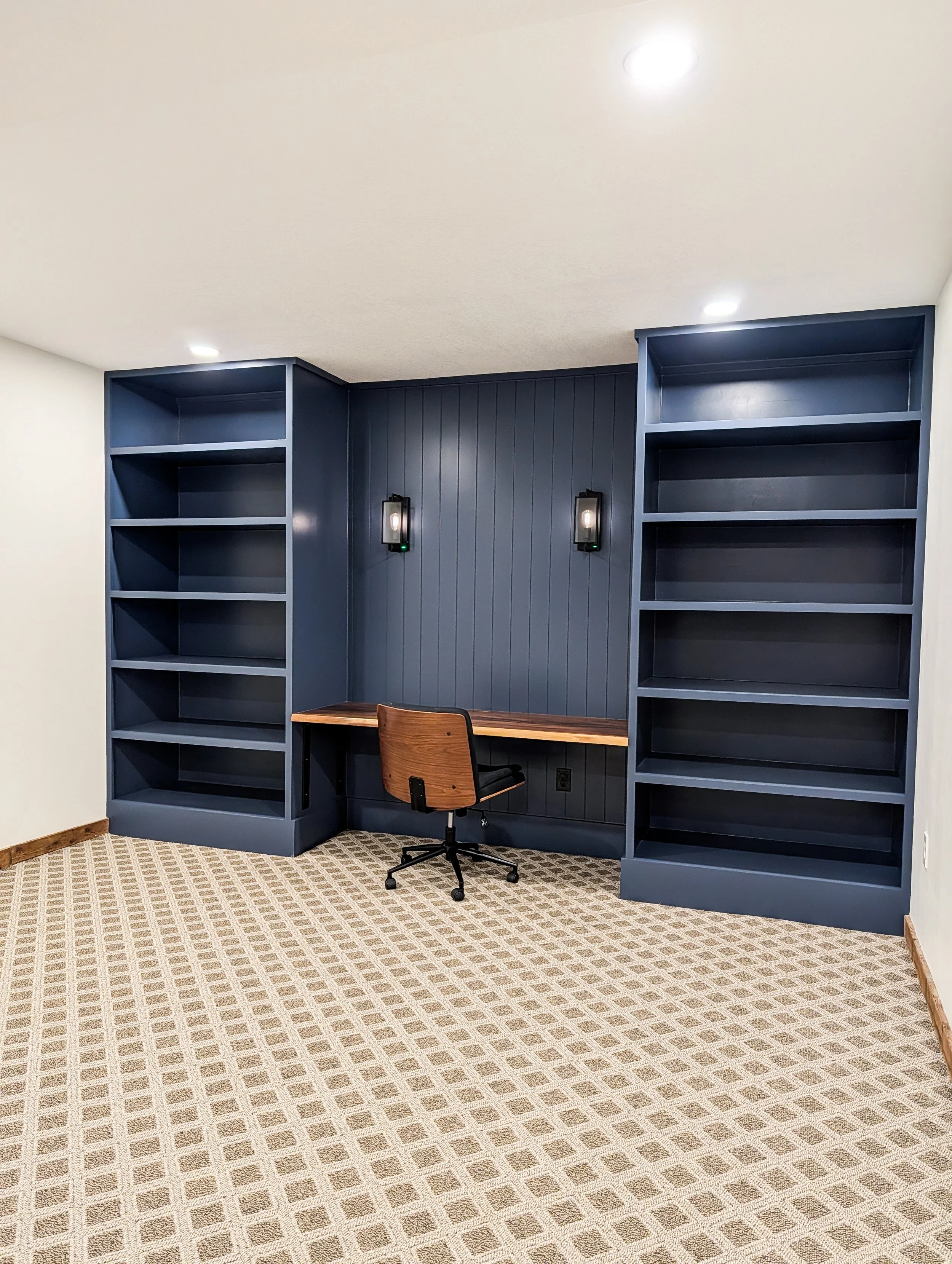 Basement office remodel in Grain Valley Missouri with blue built-in cabinetry and wall sconces