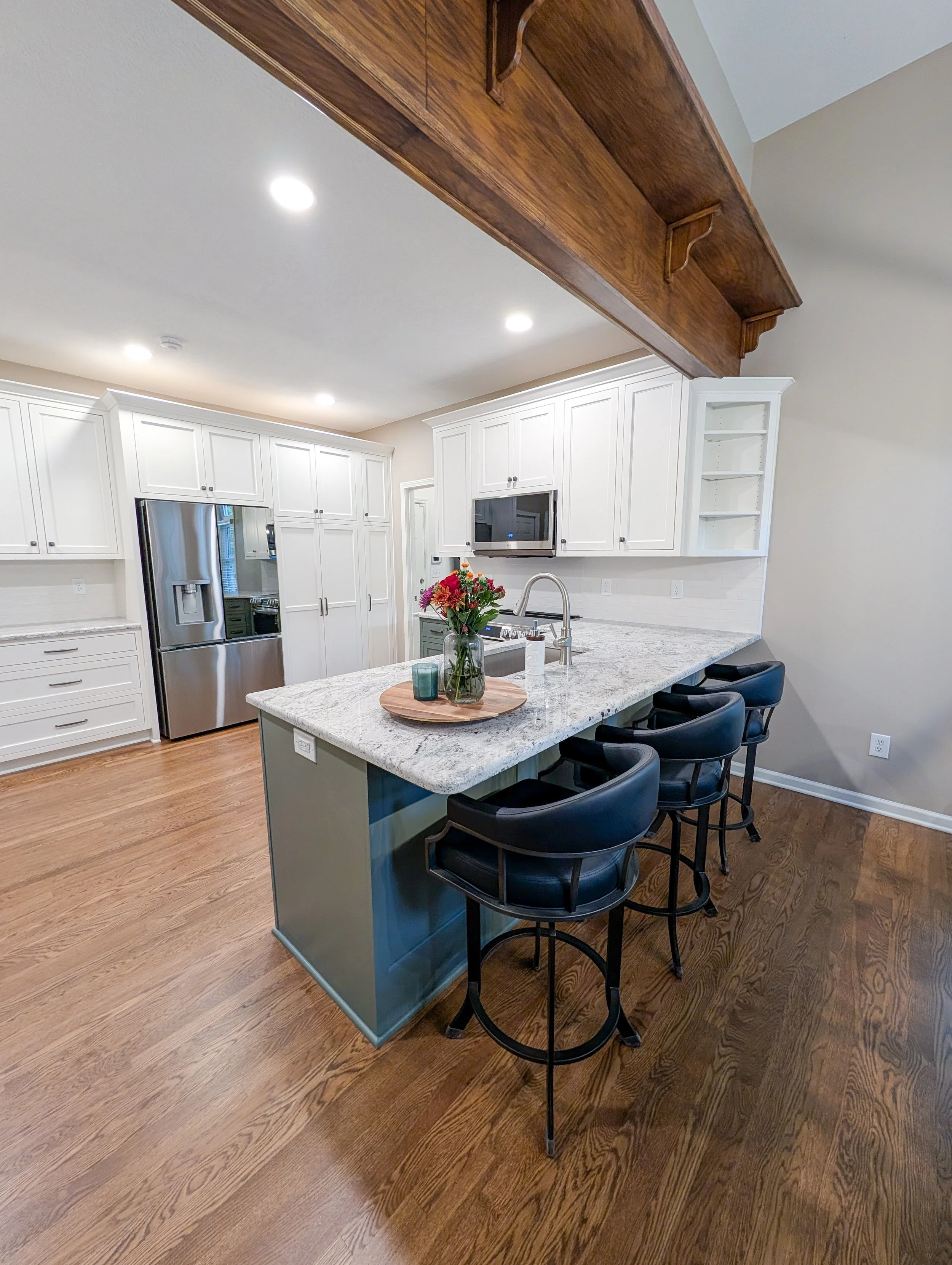 After photo of remodeled Lee’s Summit kitchen featuring two-tone white and green cabinets with new granite, and updated lighting.