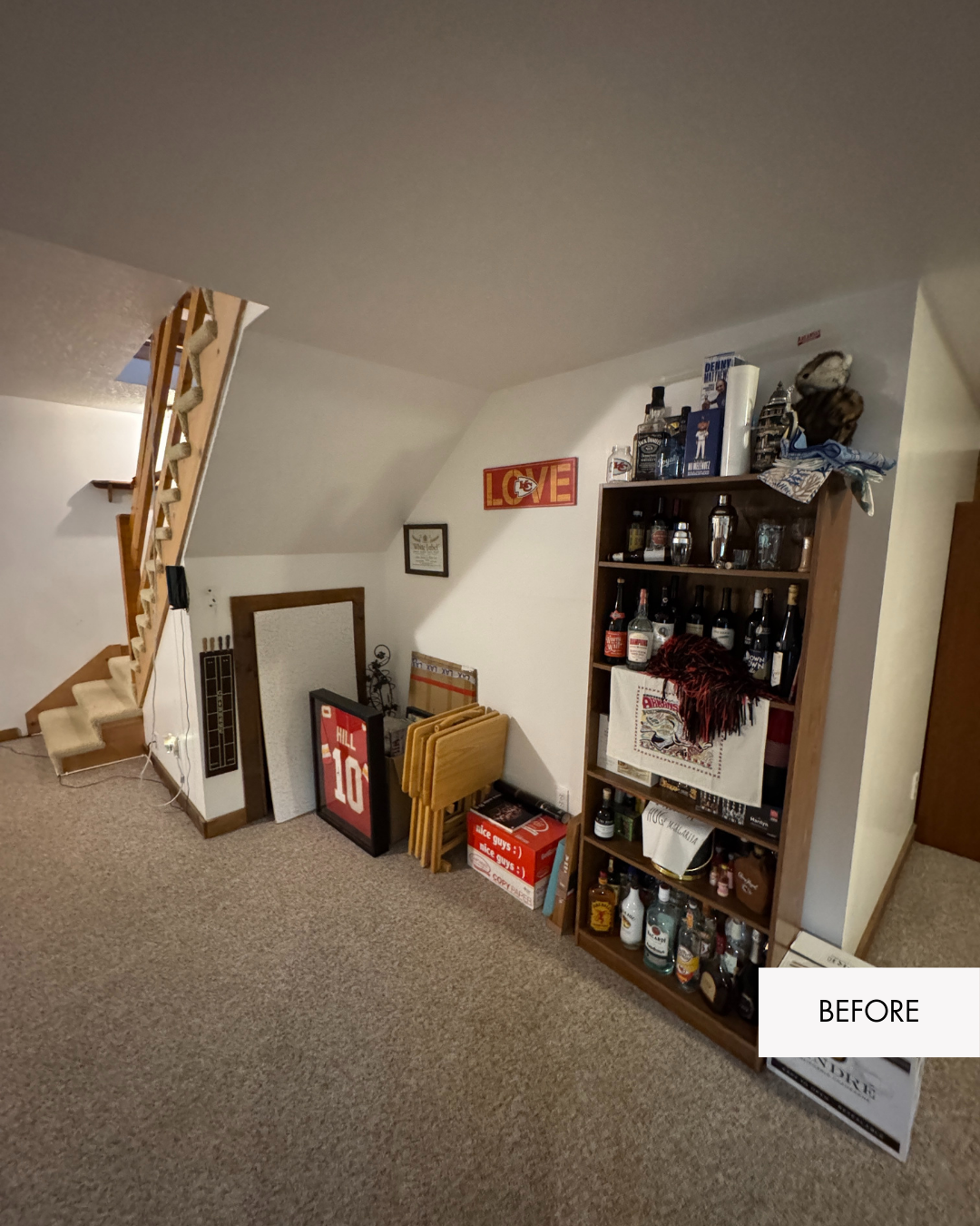 Carpeted basement before remodel with open under-stair storage in Grain Valley Missouri log cabin