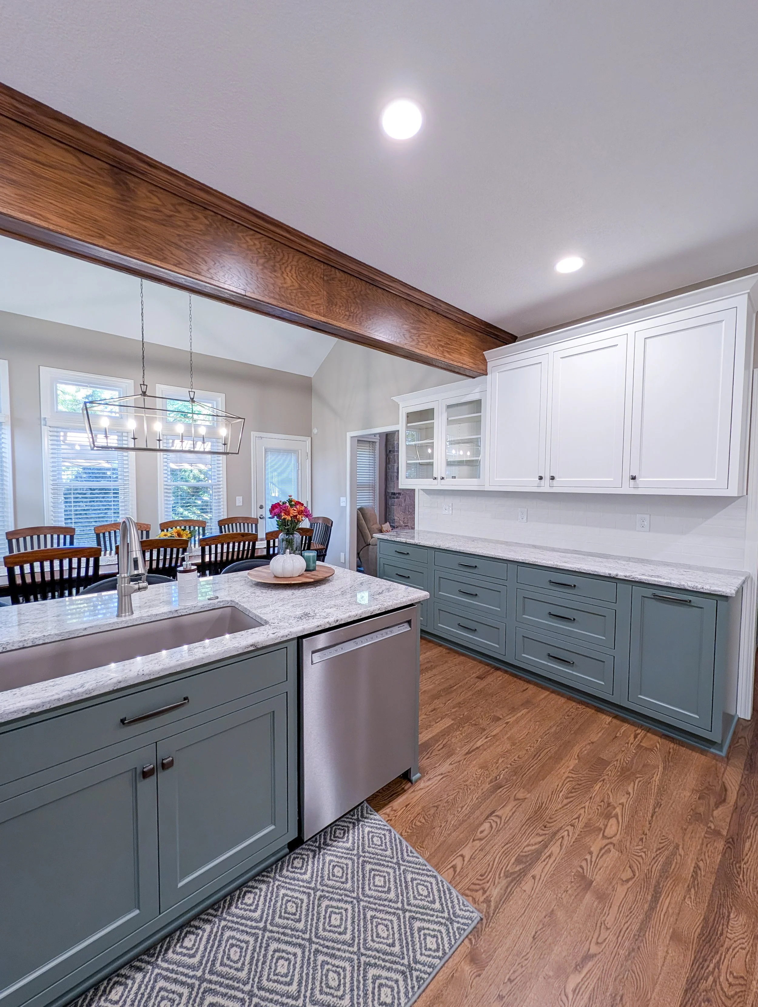 After photo of remodeled Lee’s Summit kitchen featuring two-tone white and green cabinets with new granite, and updated lighting.