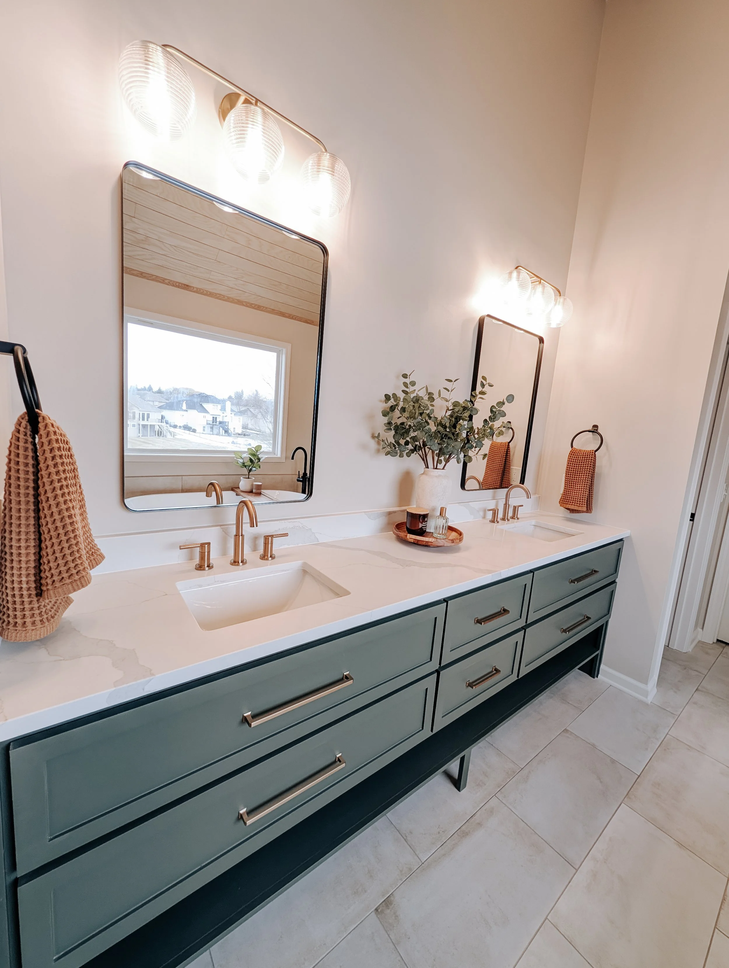 Lee's Summit bathroom remodel with gold lights, a custom green double vanity, black and gold accessories and neutral wall color and floor