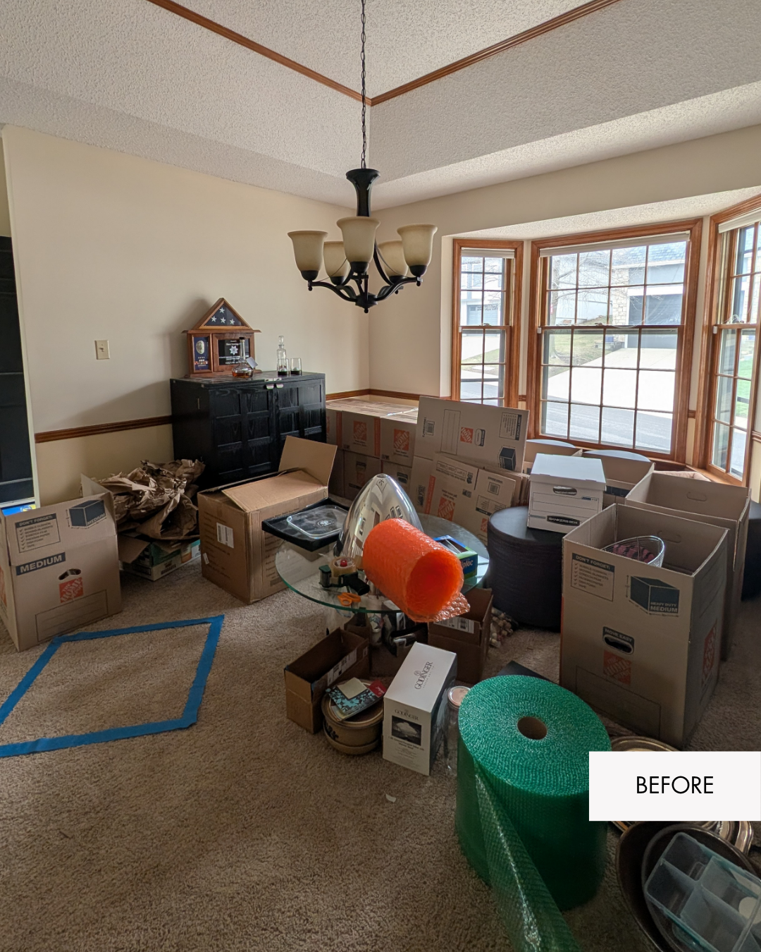 Before photo of a Lee's Summit front room, with yellow walls a dated light fixture and lots of moving boxes