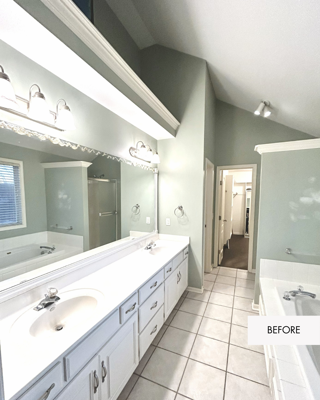 Before photo of dated Lee’s Summit primary bathroom with white vanity and large mirror