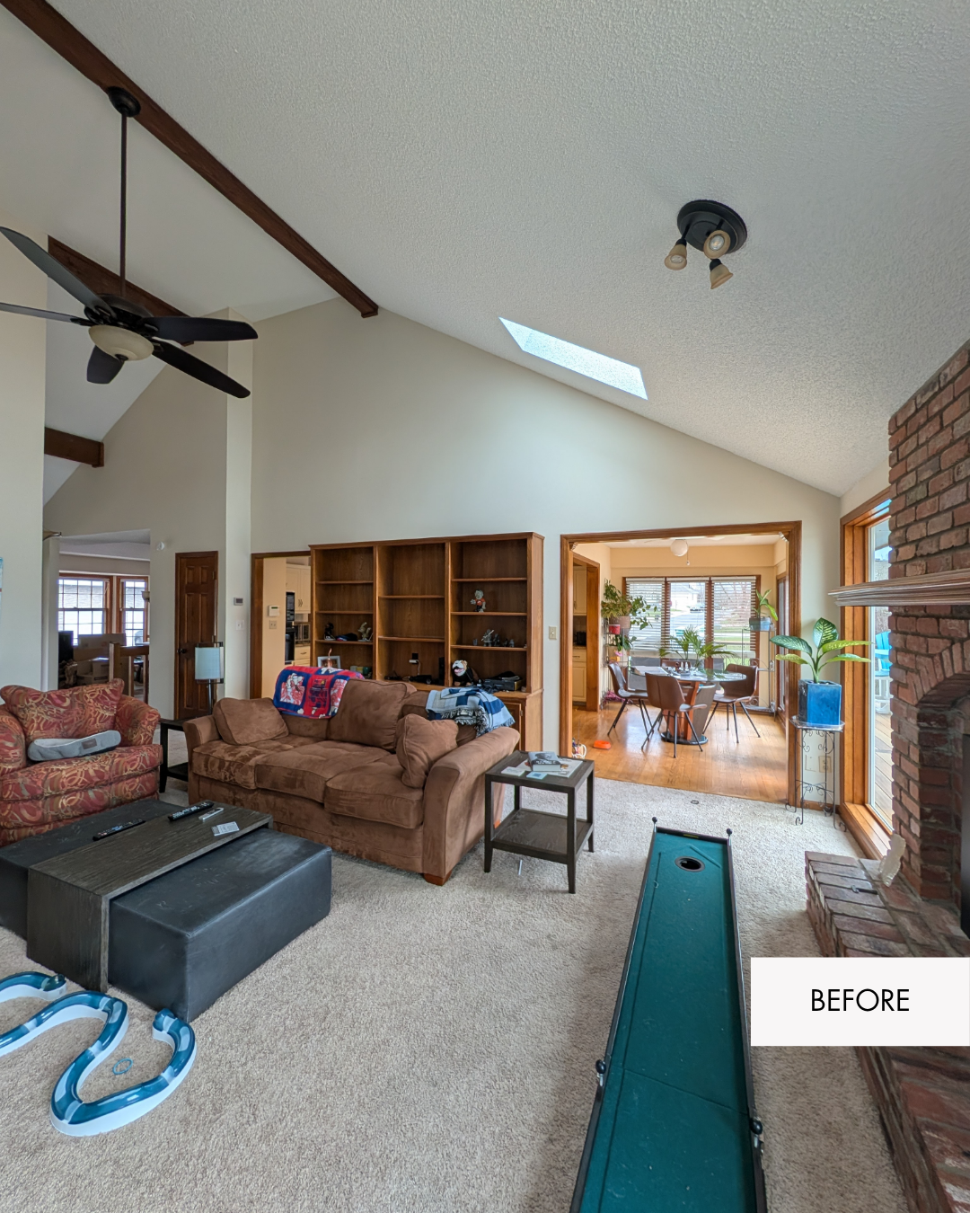 Living room before remodel with a wall and large built-in bookshelf blocking most of the view into the kitchen.