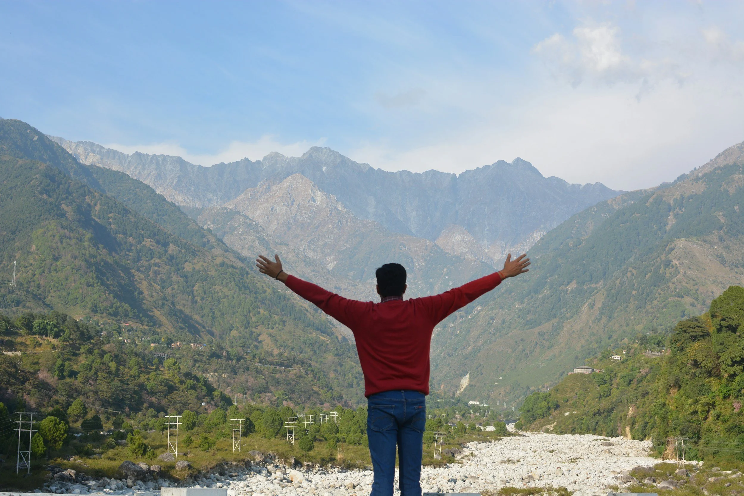 Person standing on a mountain summit with arms raised, representing The Resiliency Co.'s trauma and burnout retreats