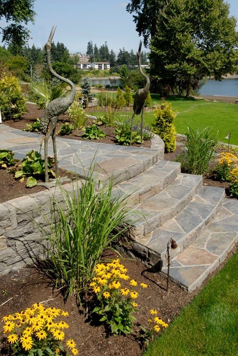 A portland landscape design project with stone steps, two crane statues, and blackeyed susan flowers.
