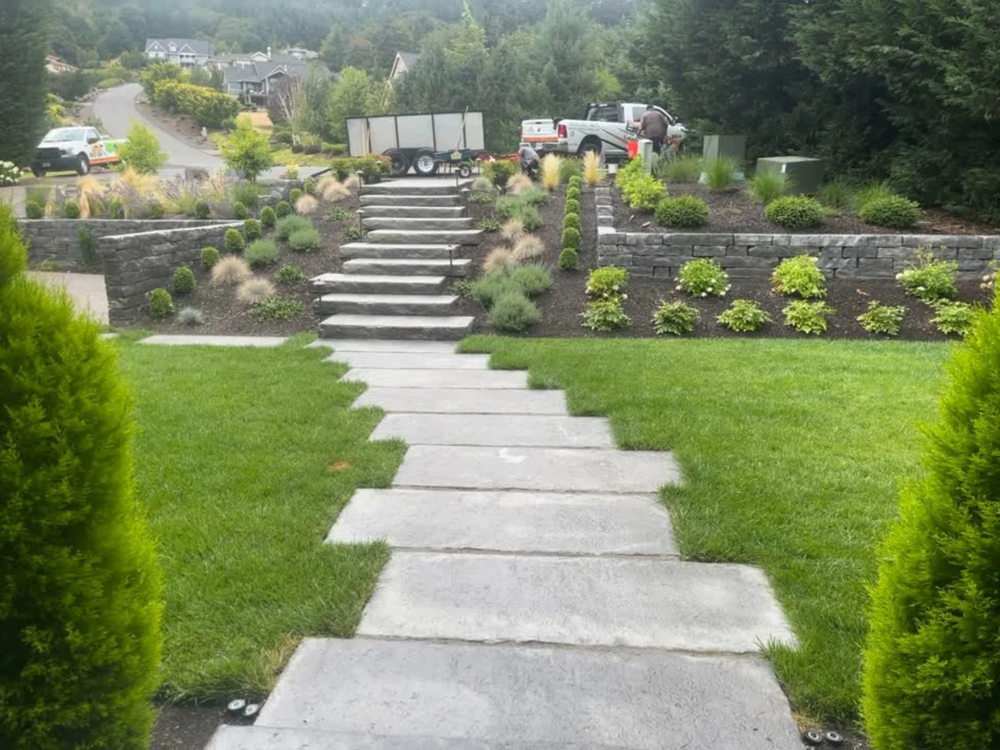 A manicured lawn with symmetrical pavers leading to steps placed amongst a fully finished landscape design, all completed by Big Sky Landscaping. 