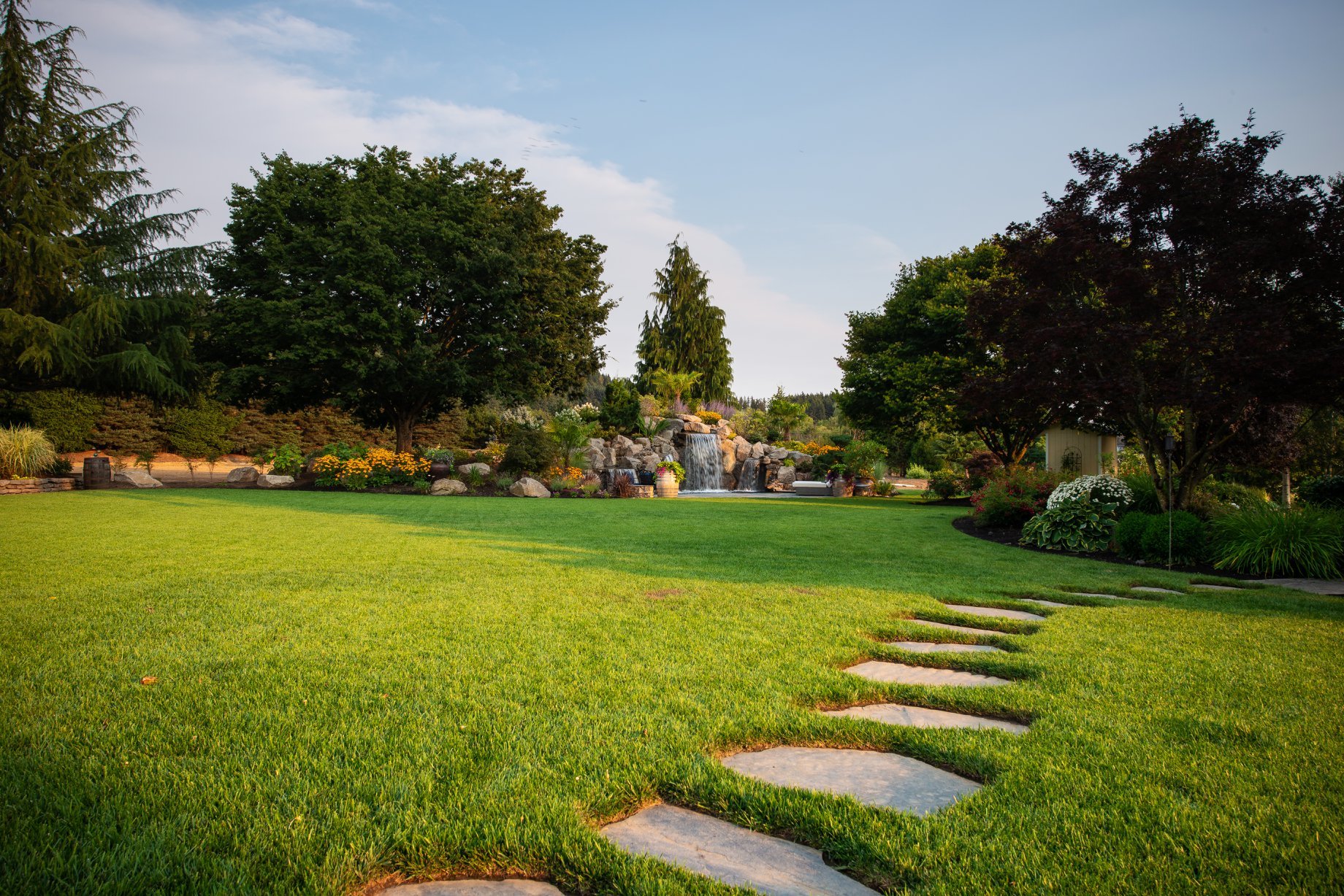 A faraway shot of a waterfall and landscape structure installed by Big Sky Landscaping for a residential landscaping client in Happy Valley, OR. 