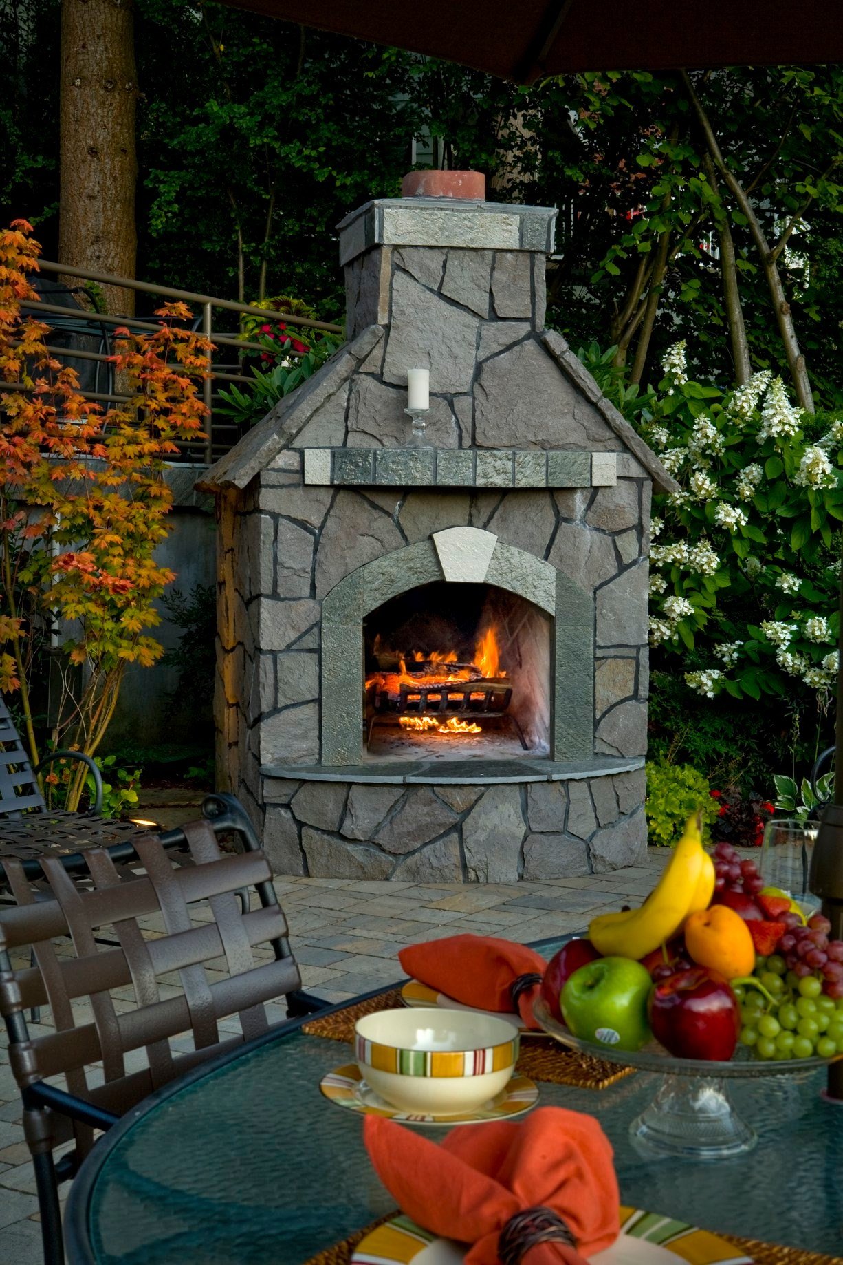 An upclose picture of a stone fireplace surrounded by floral landscaping installed by Big Sky Landscaping in Happy Valley. 