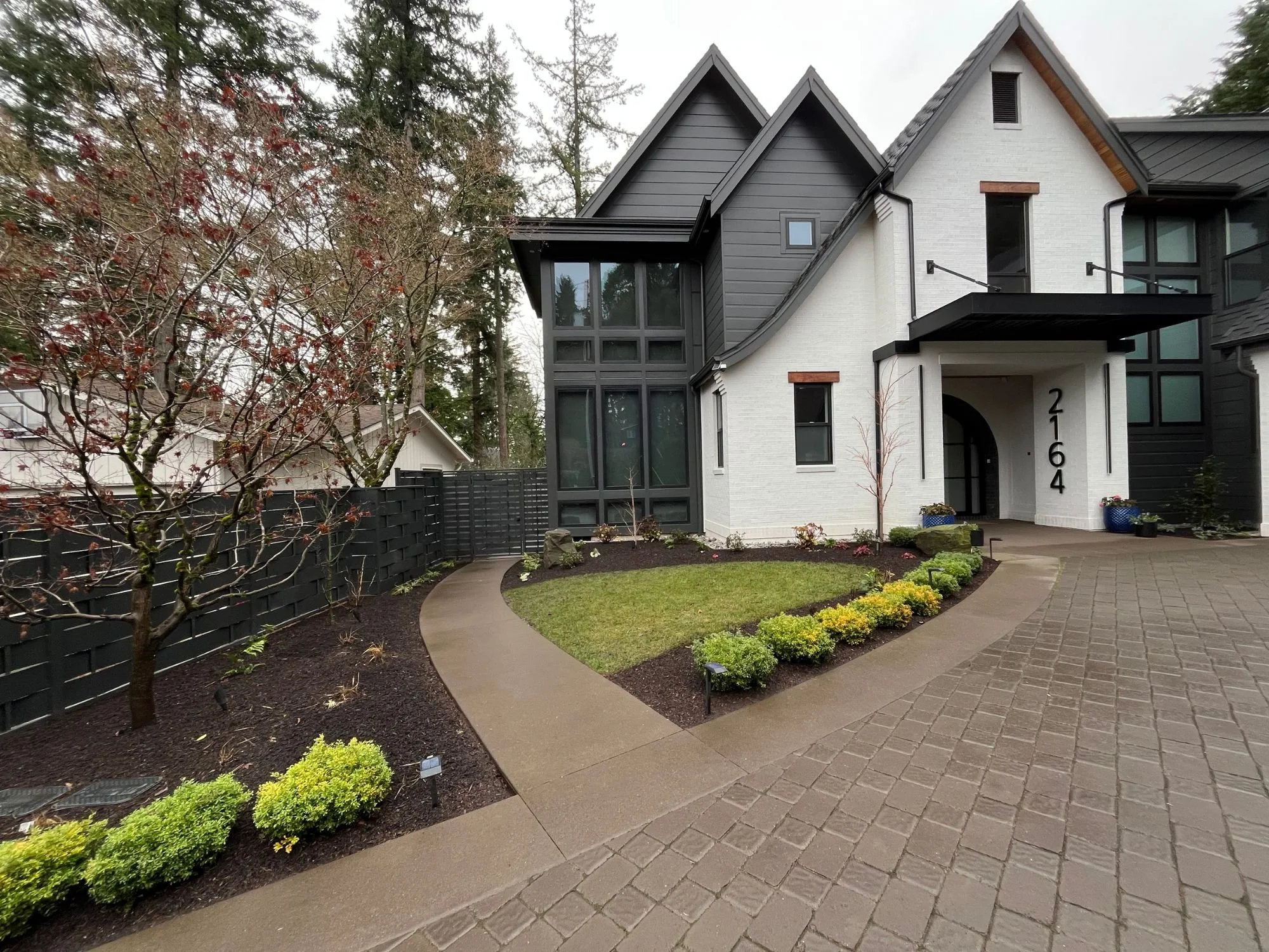A modern Lake Oswego home with a driveway adorned by beautiful landscaping on the sides. 