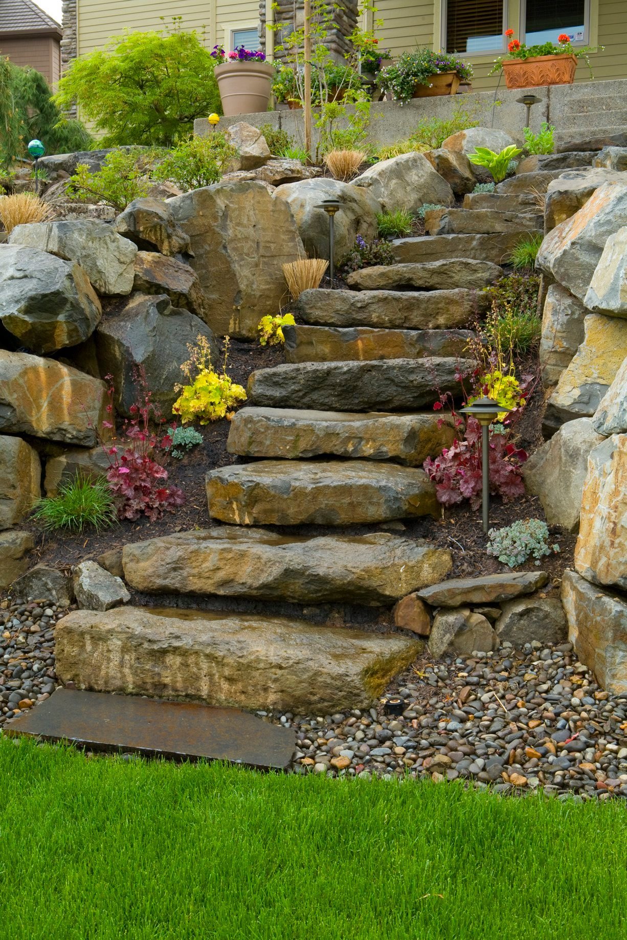 A depiction of stone steps lined with native Portland plants in a backyard oasis created by Big Sky Landscaping.