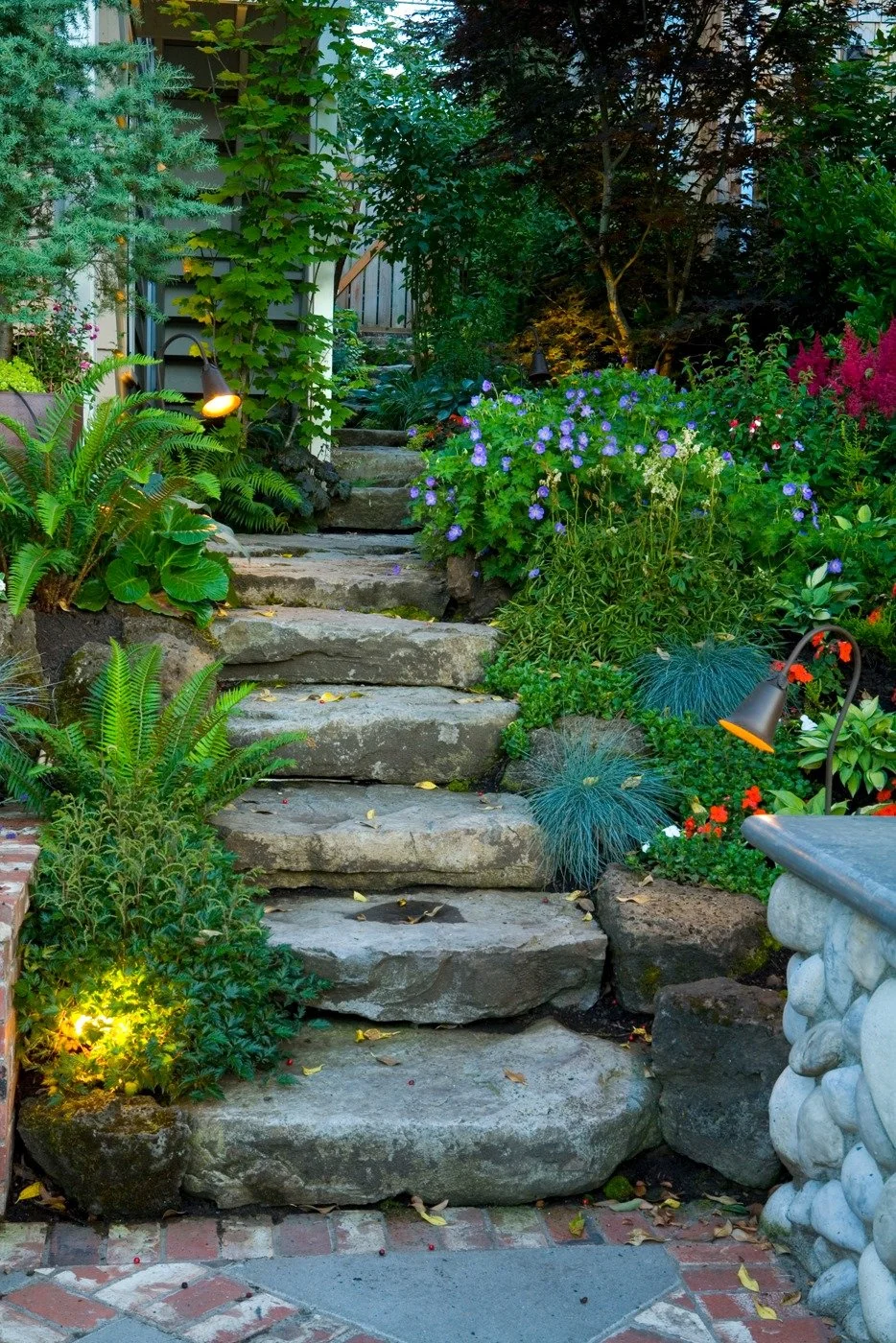 Natural flagstone steps are illuminated by path lights, guiding visitors through a lush Hillsboro yard.
