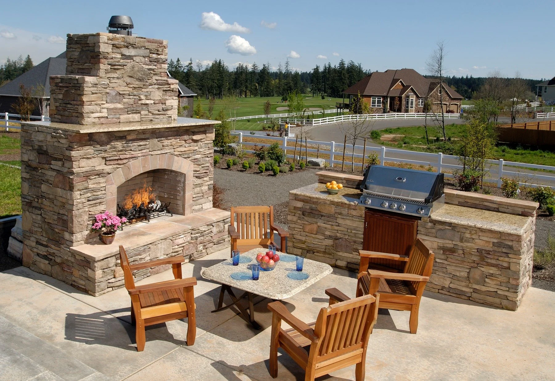 A fully equipped outdoor stone kitchen and fireplace overlook a sprawling Wilsonville estate and nearby golf course.