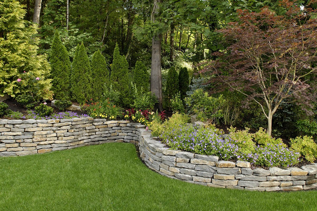 A retaining wall and landscaping designed and installed by Big Sky Landscaping in the backyard of a residential home in West Linn, OR.