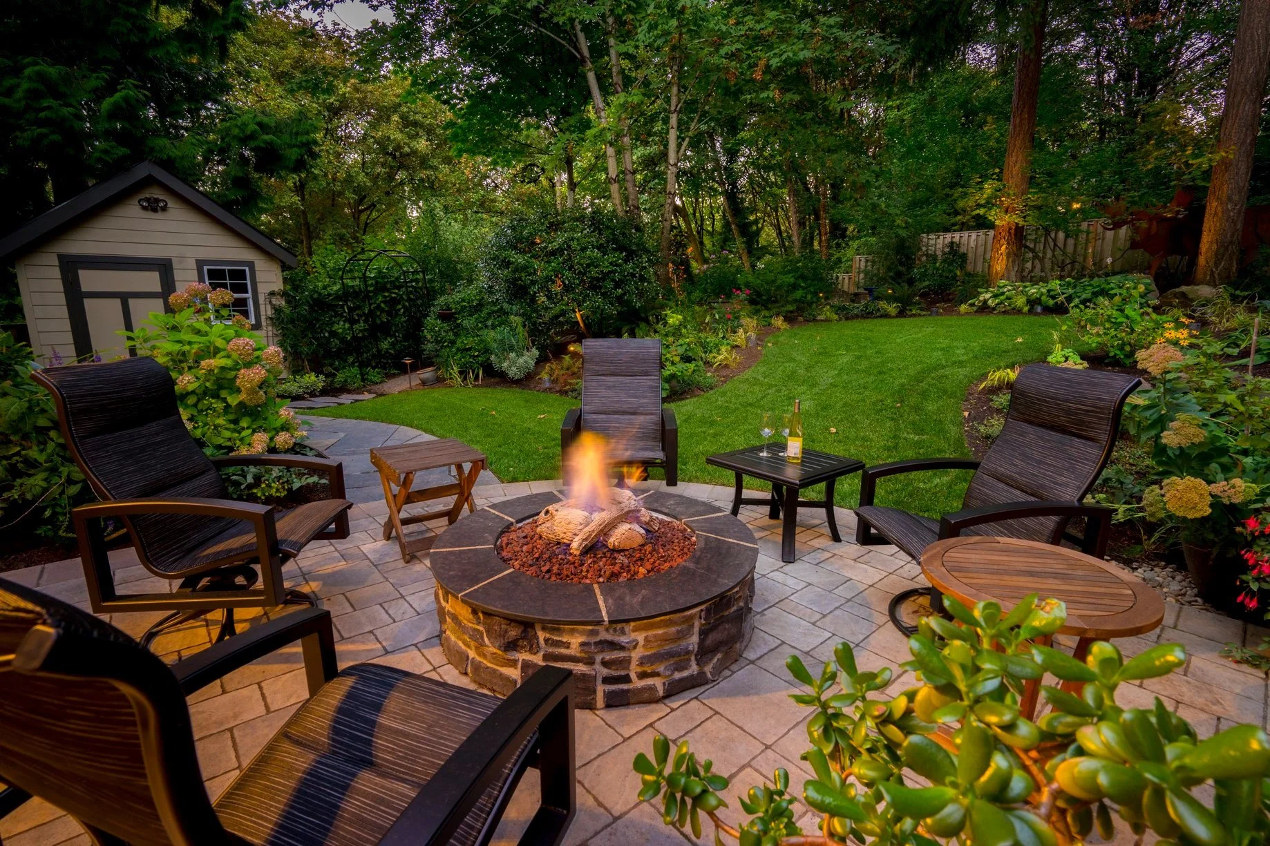 A cozy backyard retreat in Wilsonville includes a circular stone fire pit and a lush, green lawn designed by a premier Wilsonville landscape design team.
