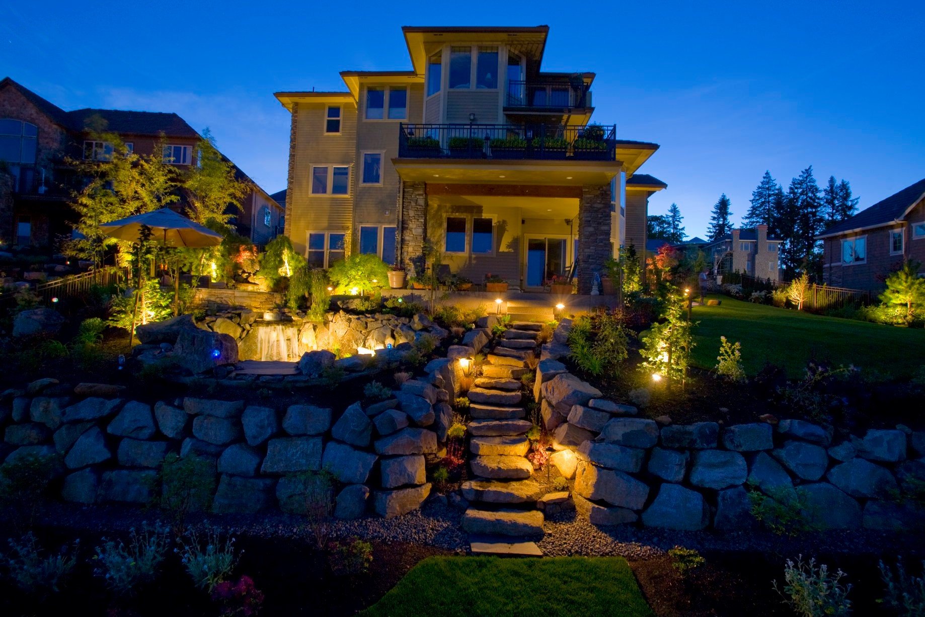 This multi-level Oregon City backyard features illuminated stone steps and tiered retaining walls that glow beautifully at dusk.