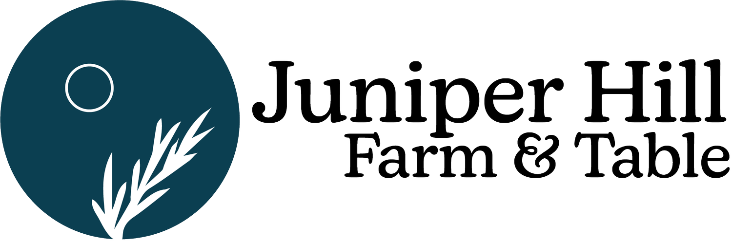 Logo of Juniper Hill Farm & Table with a circular design containing an abstract juniper branch and a small circle, representing the moon or sun.