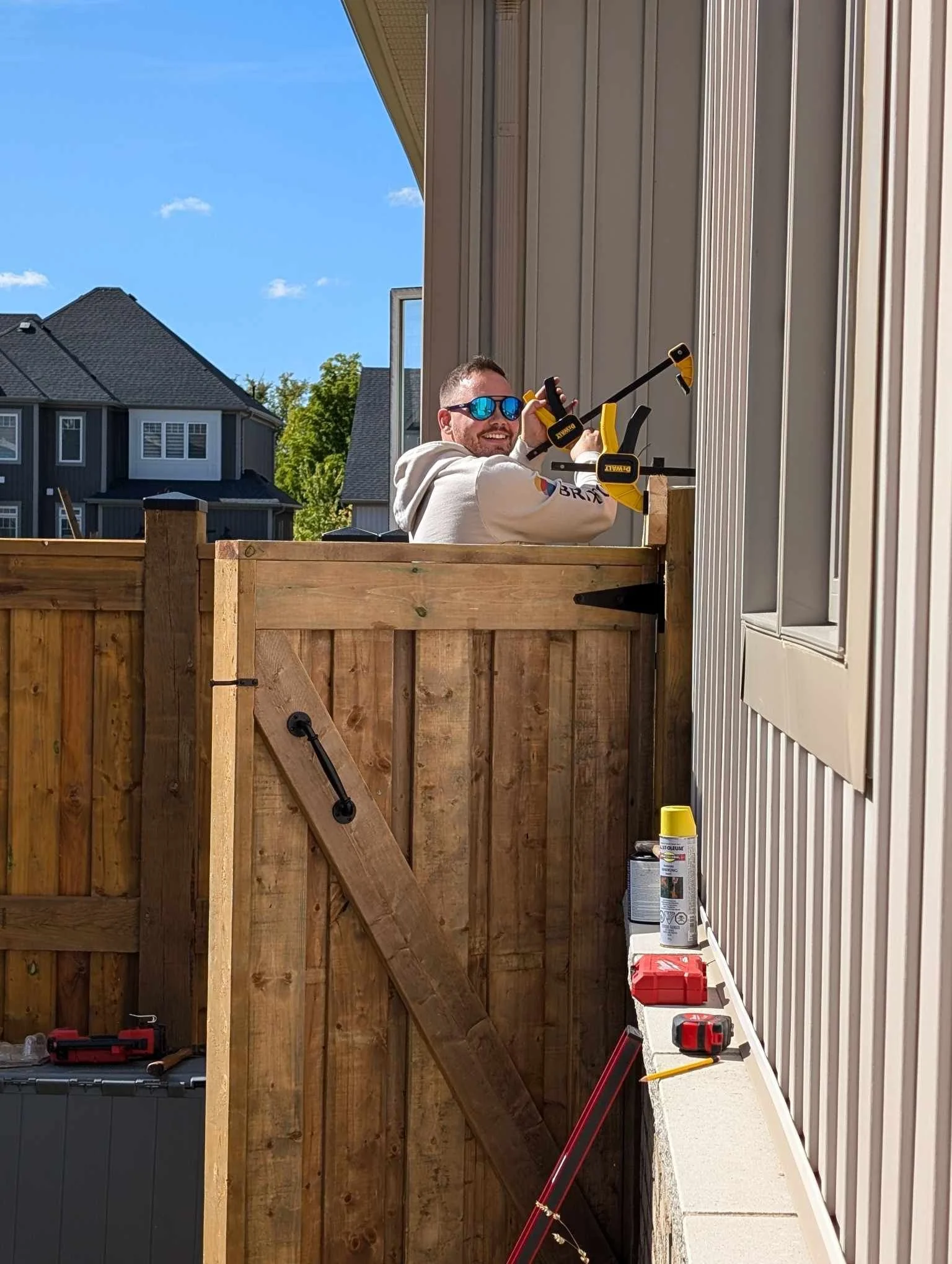 Wooden vertical fence with visible knots, small plants at the base.