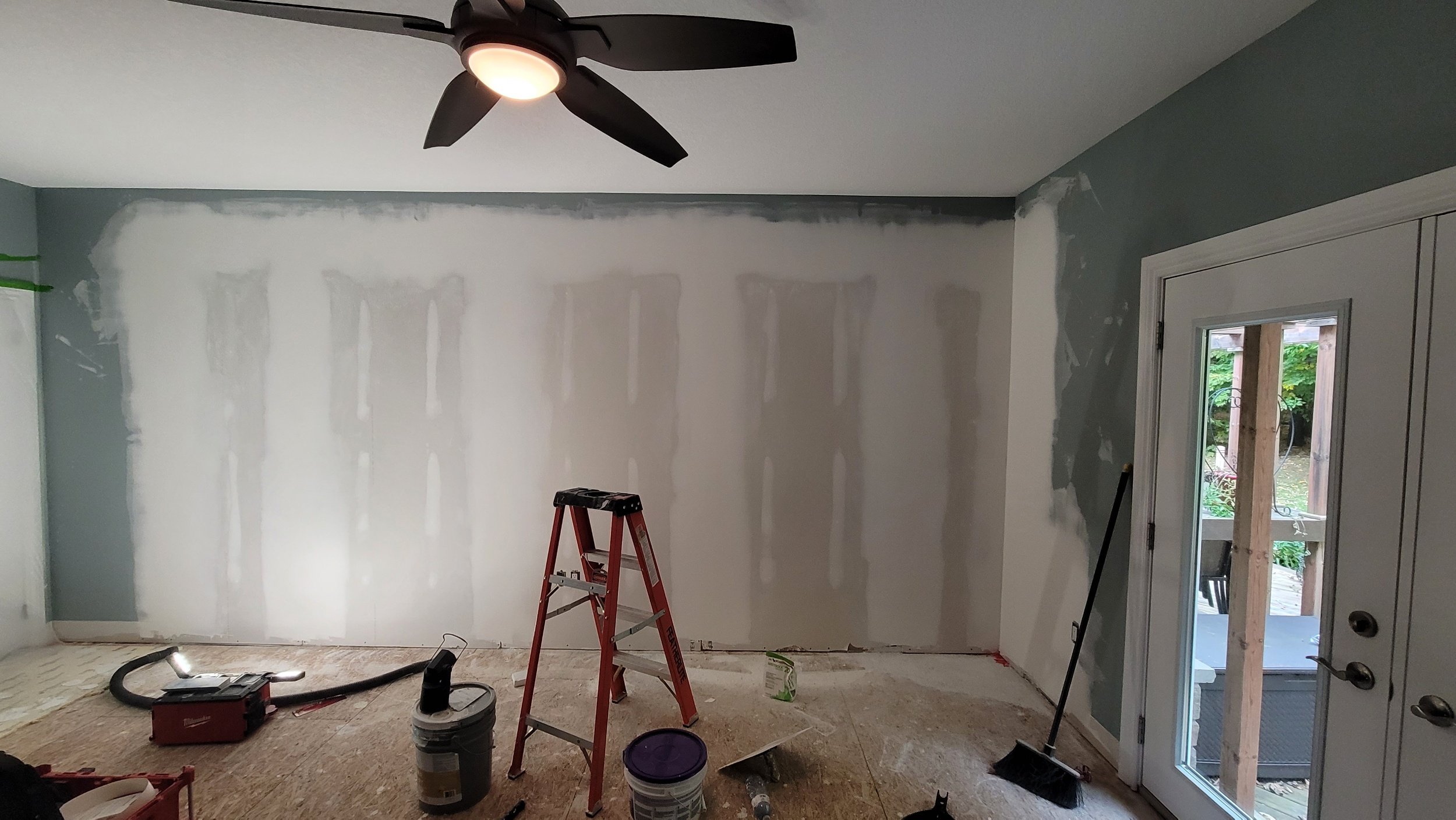 Person cutting a hole in drywall with a hand saw.