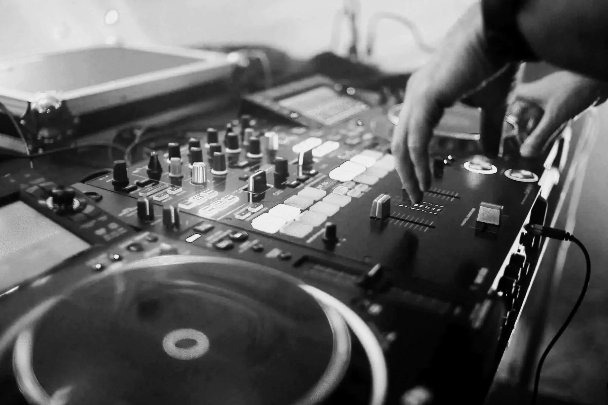 Mano manipulando consola de DJ en un escenario.