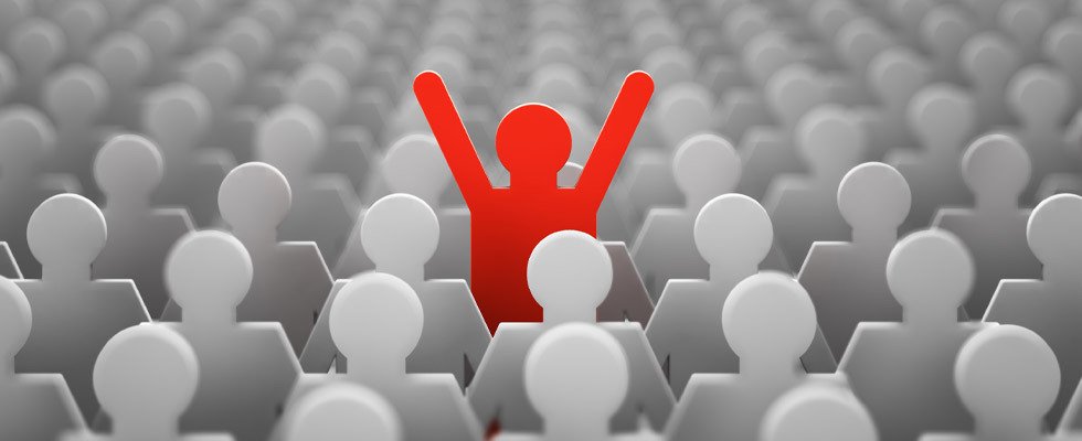 a red paper figure standing up among a sea of sitting white paper figures