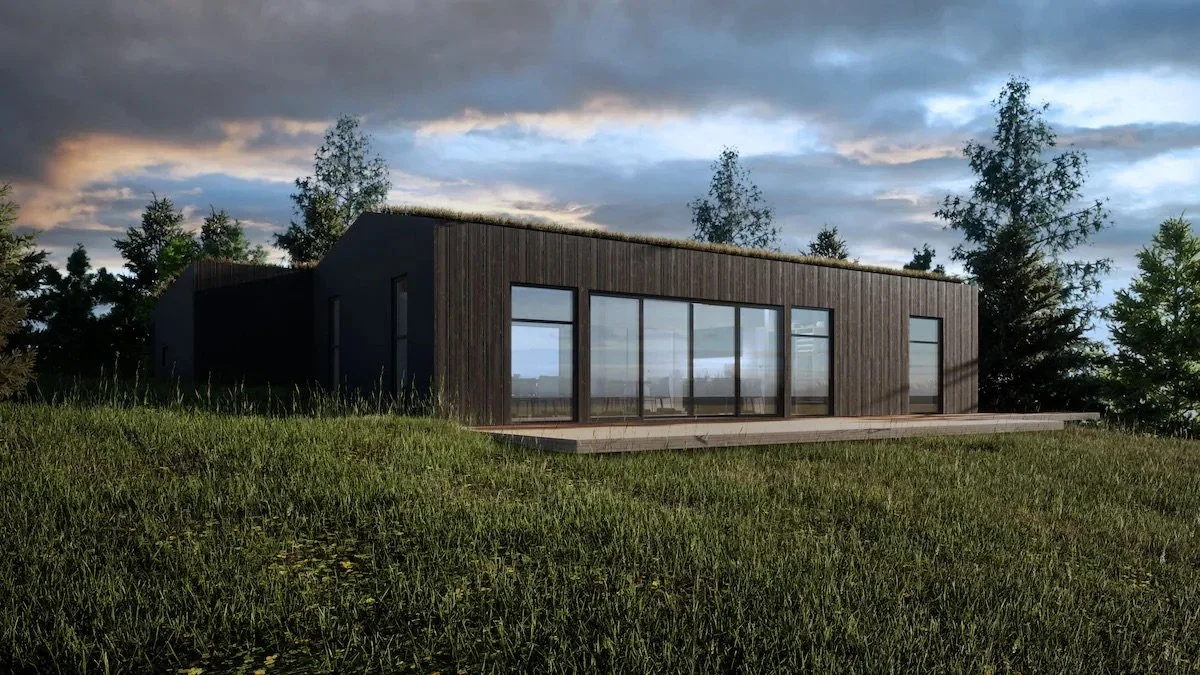 Modern dark wooden house with large glass windows on a grassy hill with trees in the background and a cloudy sky.