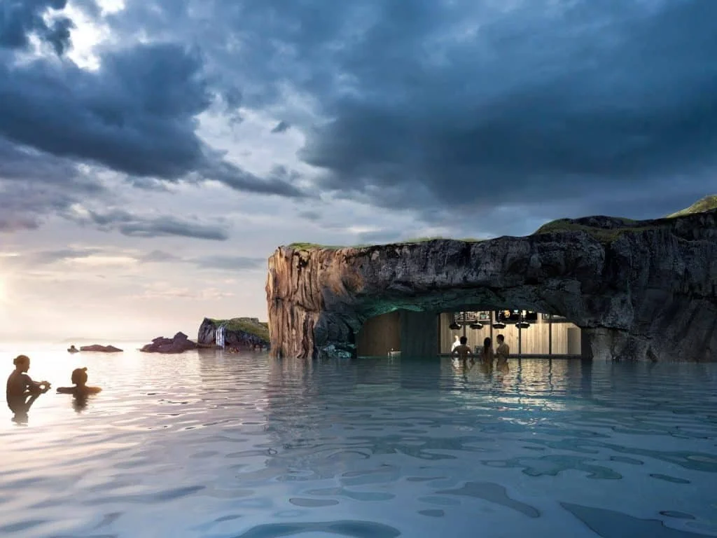 People swimming in an ocean pool with rocky formations and caves, under a cloudy sky.