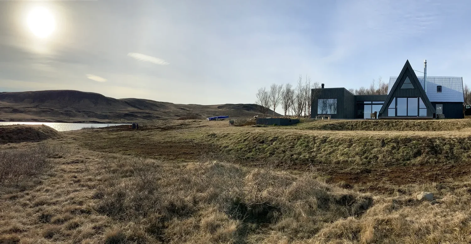 The black A-frame lakefront home on Lake Gíslholtsvatn
