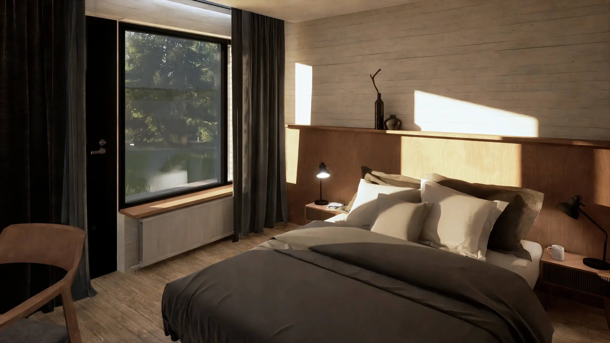 A bedroom with sloped ceiling walls. The bed has white sheets, gray and blue pillows, and navy bedding. Towels are folded on the bed. The room has a built-in gray cabinet under a small rectangular window with decorative items on the windowsill.