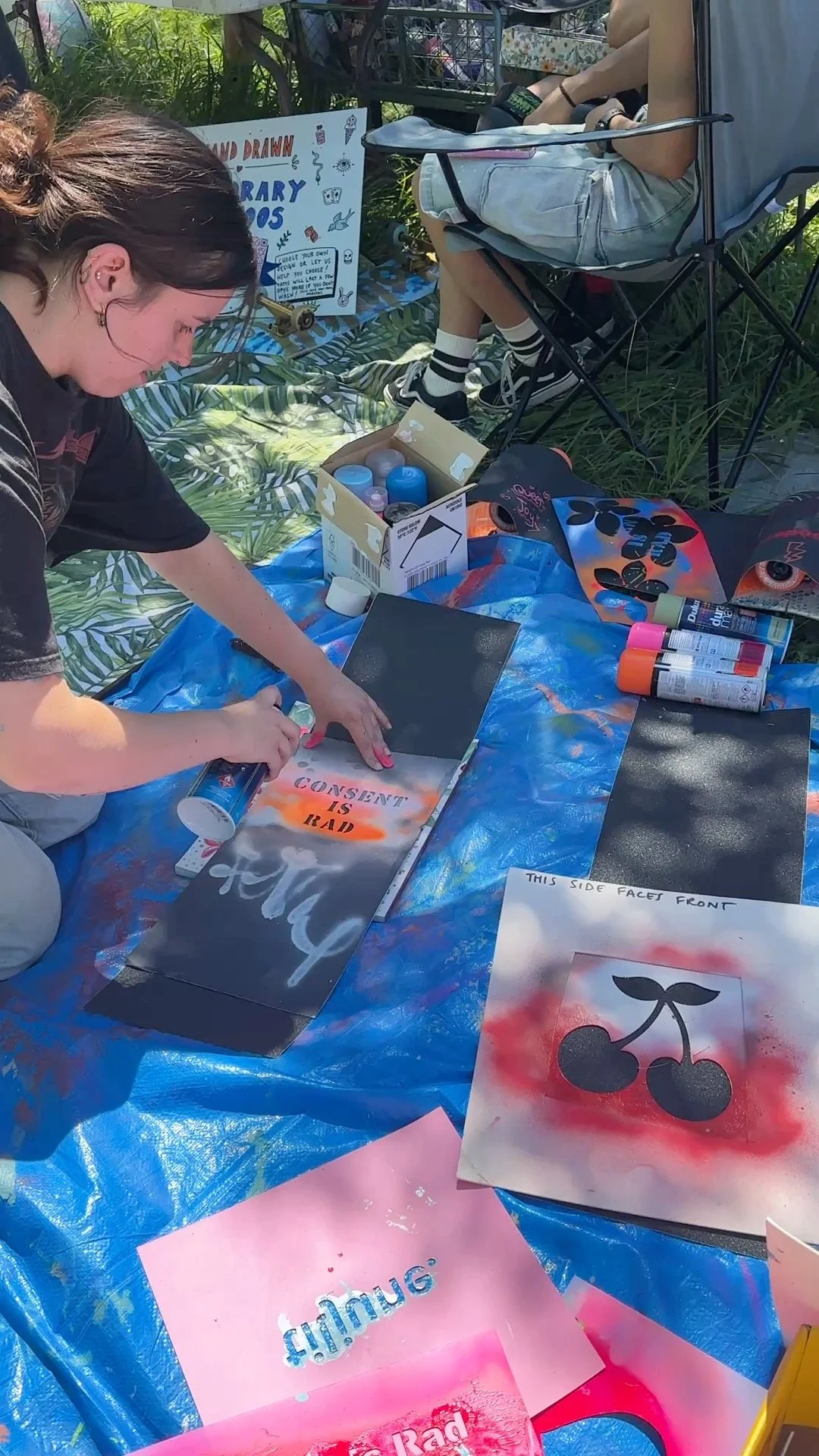 Miriam enjoying spraypainting on grip tape a Consent is Rad @respectisrad stencil, one of many this year at the art station. Photo by Indigo Willing @goodwillinghunting. 
