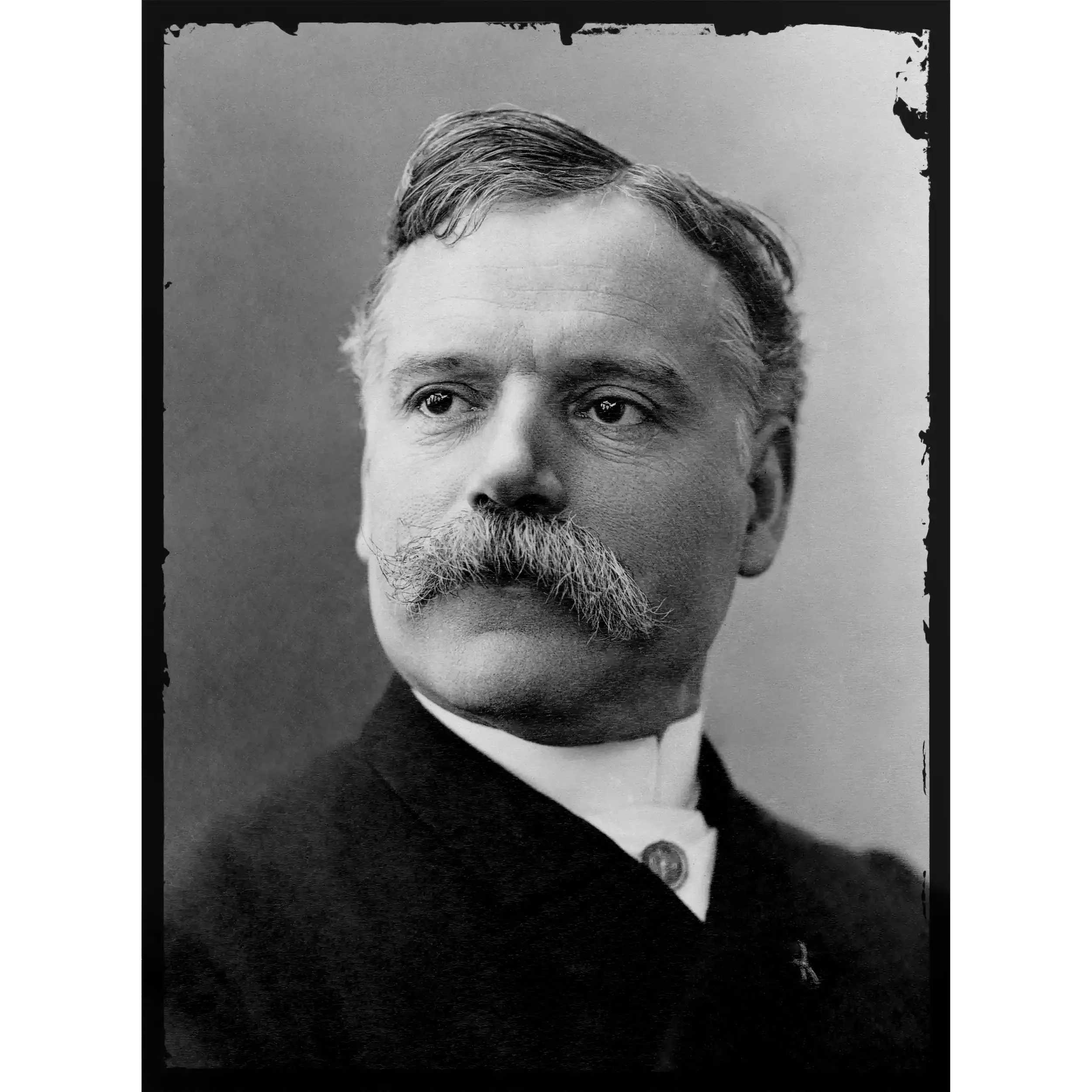 Black and white photo of a middle-aged man with a beard and mustache, wearing a suit and tie.