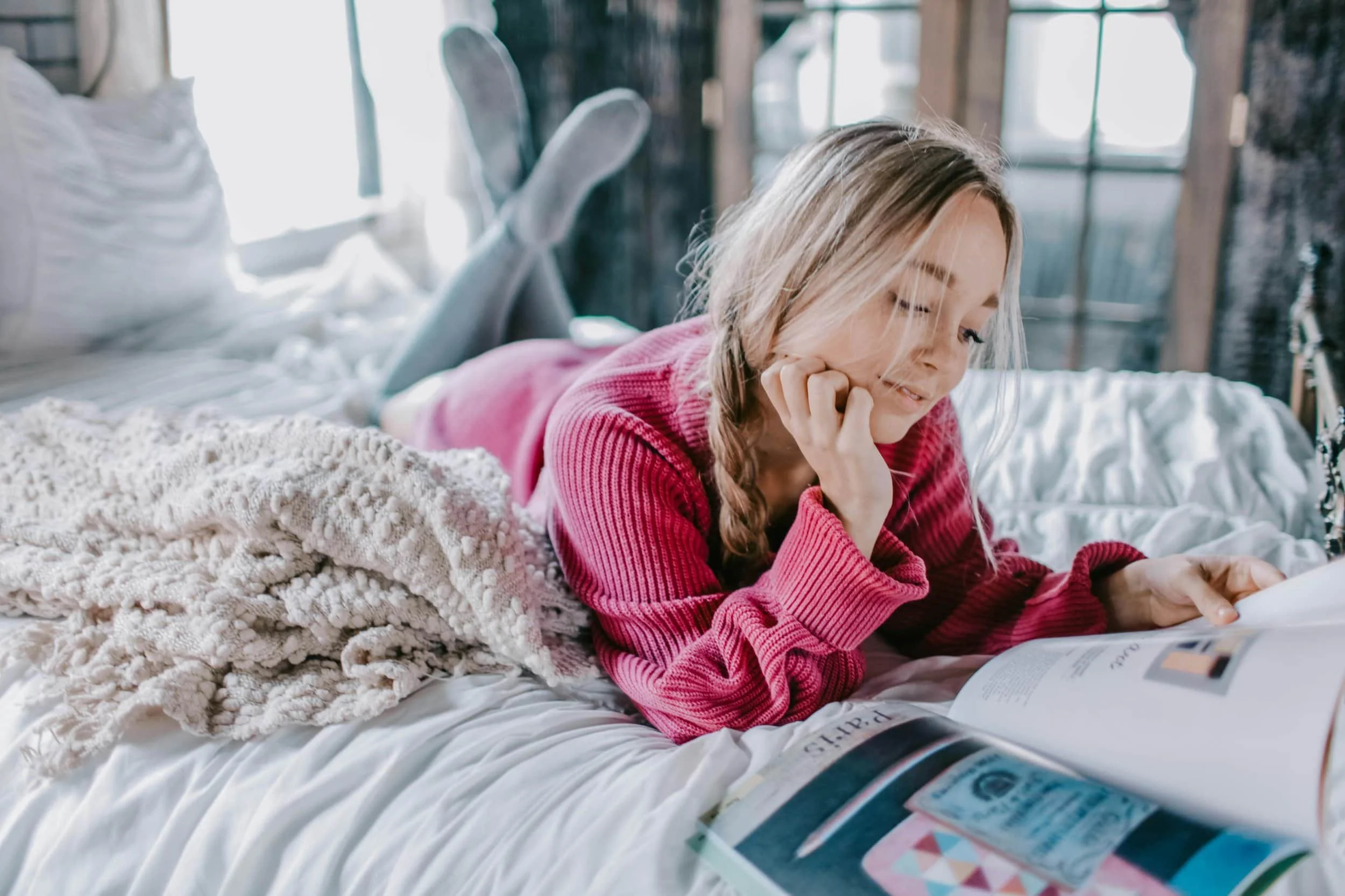 Woman reading magazine on bed feeling happy