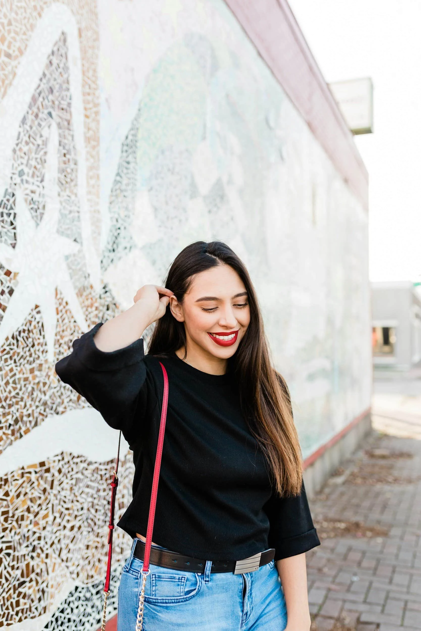 Woman smiling standing in front of mosaic wall mural