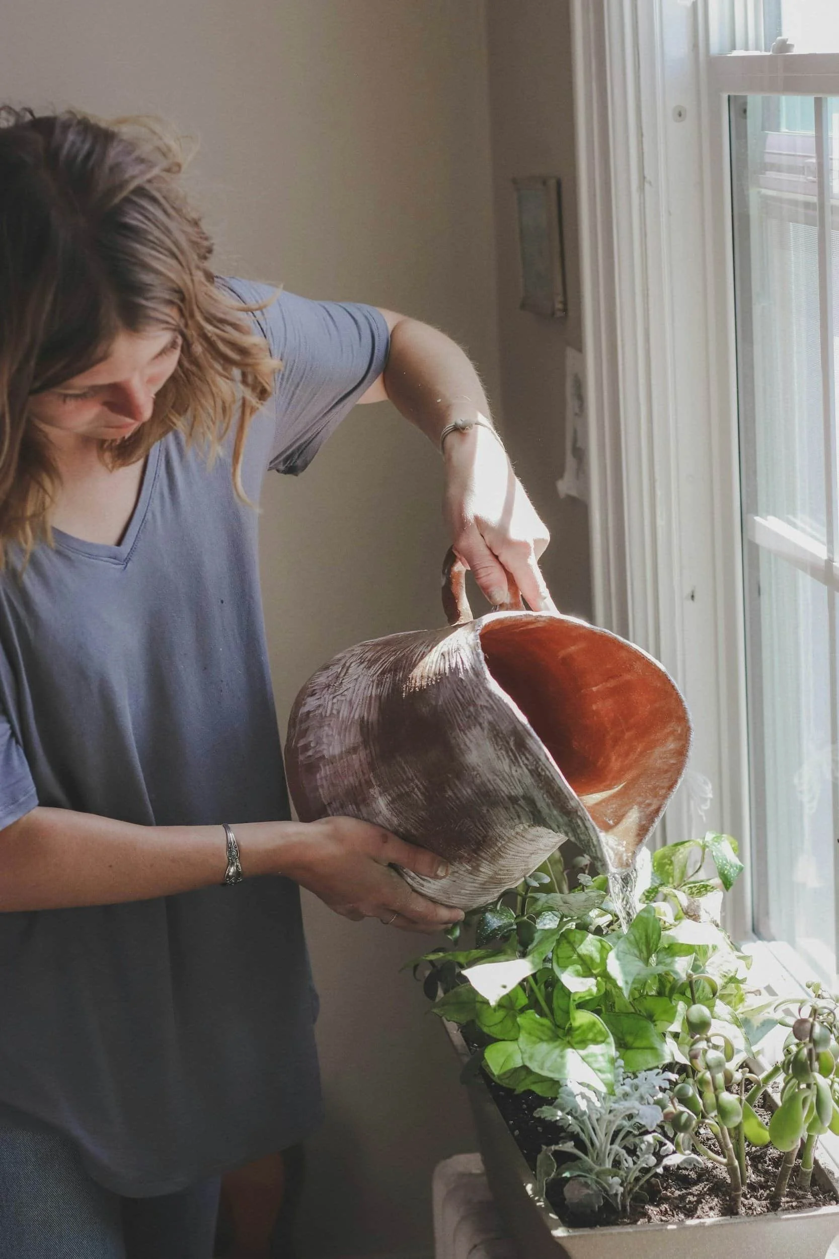 woman watering plants by window