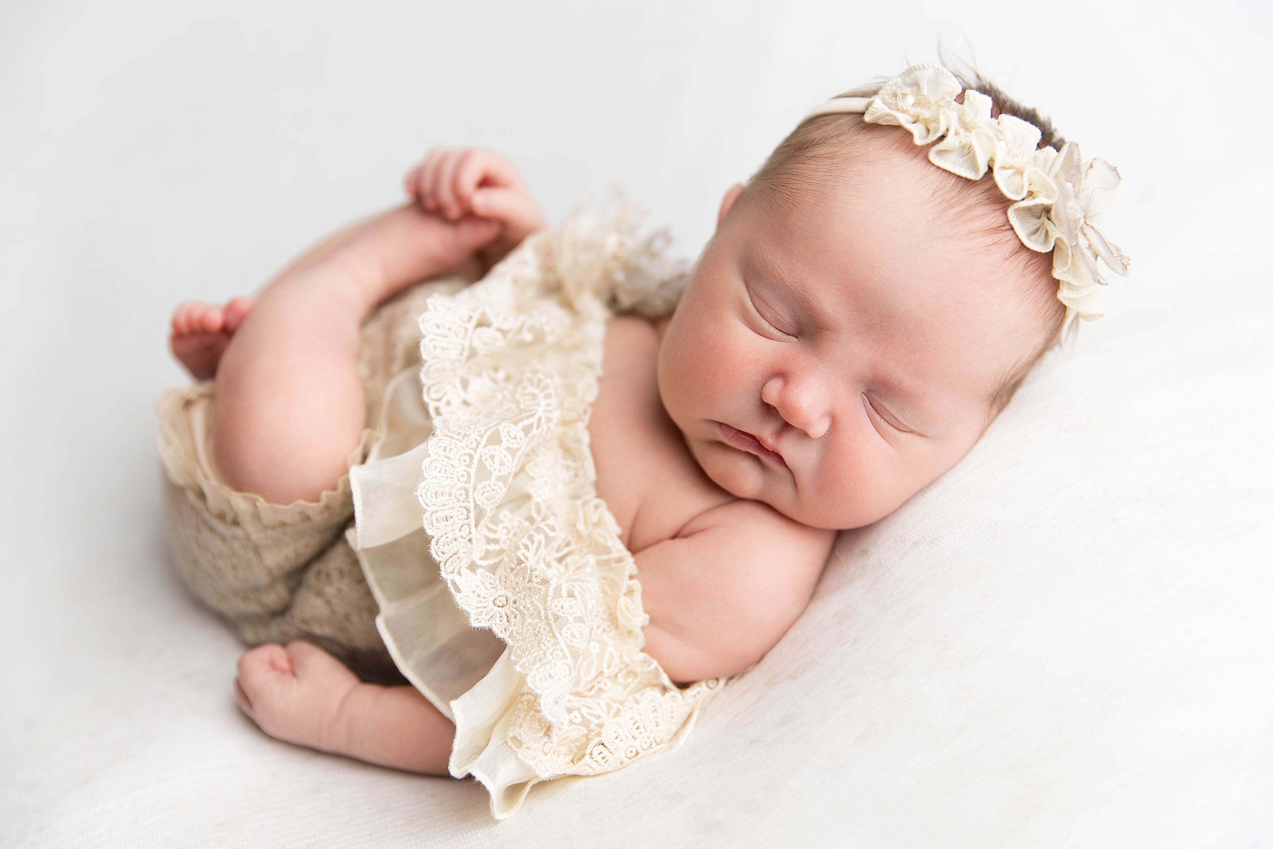 Posed newborn baby girl sleeping peacefully in a neutral studio setup during a newborn photography session