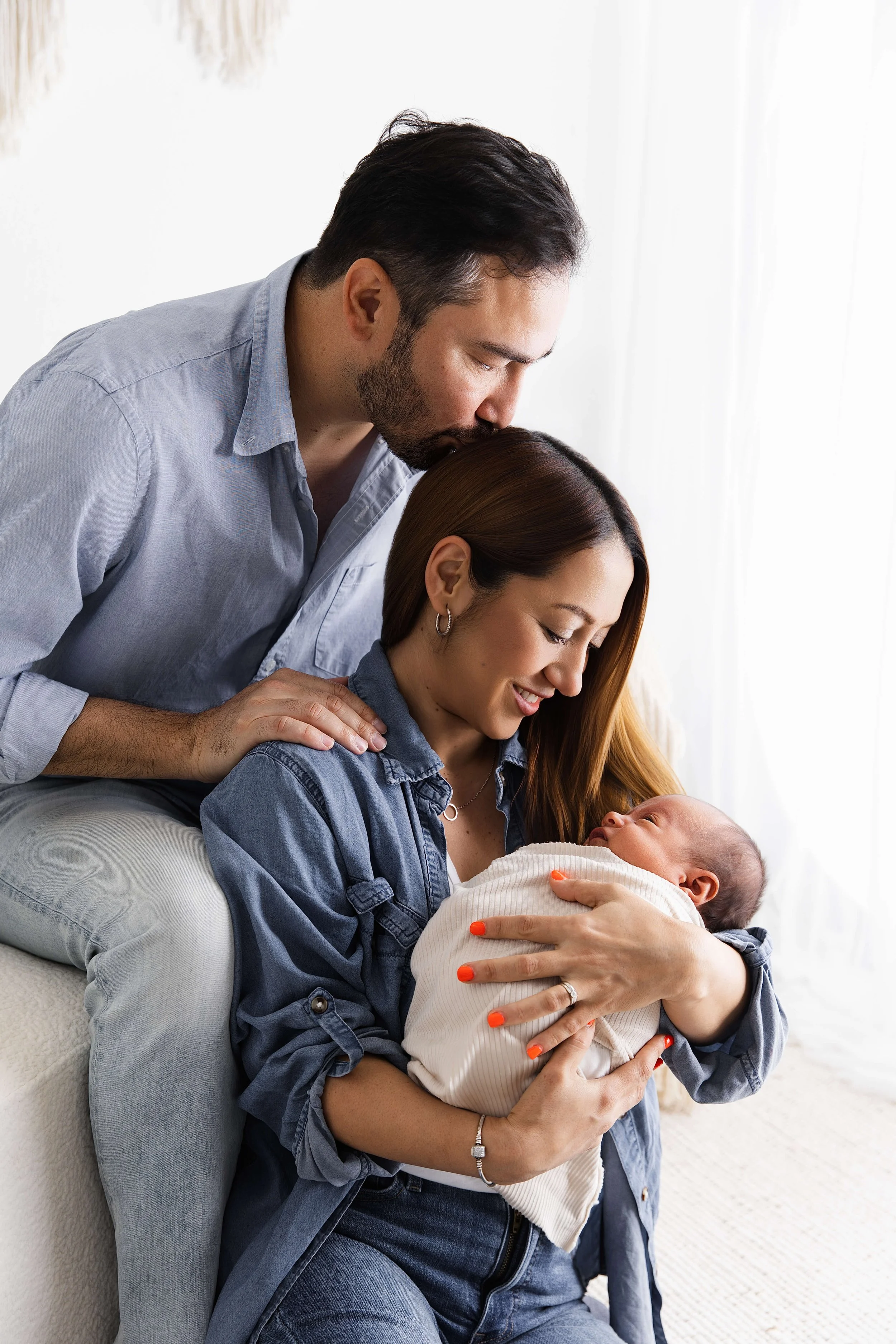 dad kissing mom cuddling with newborn