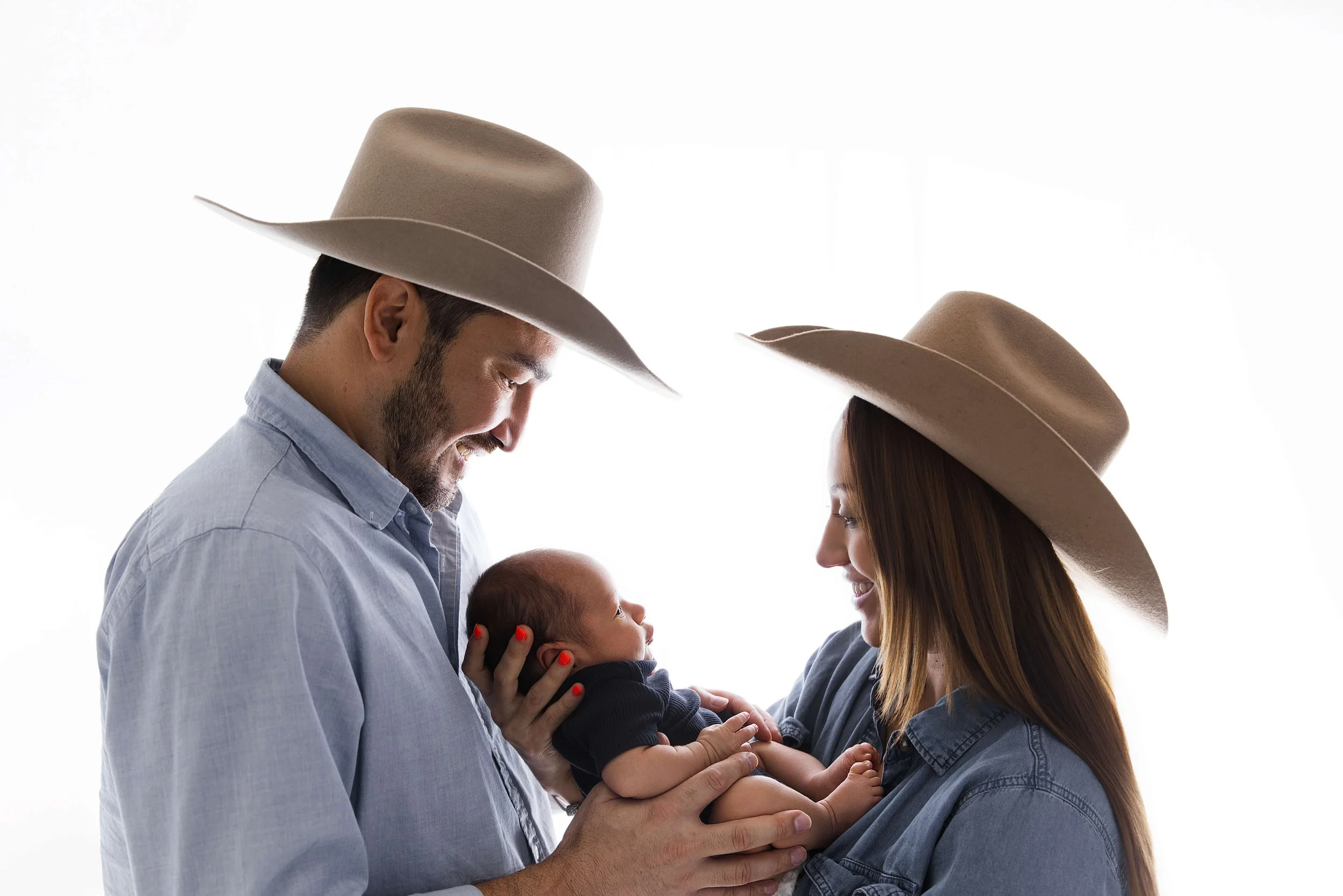 parents with newborn cowboy hats