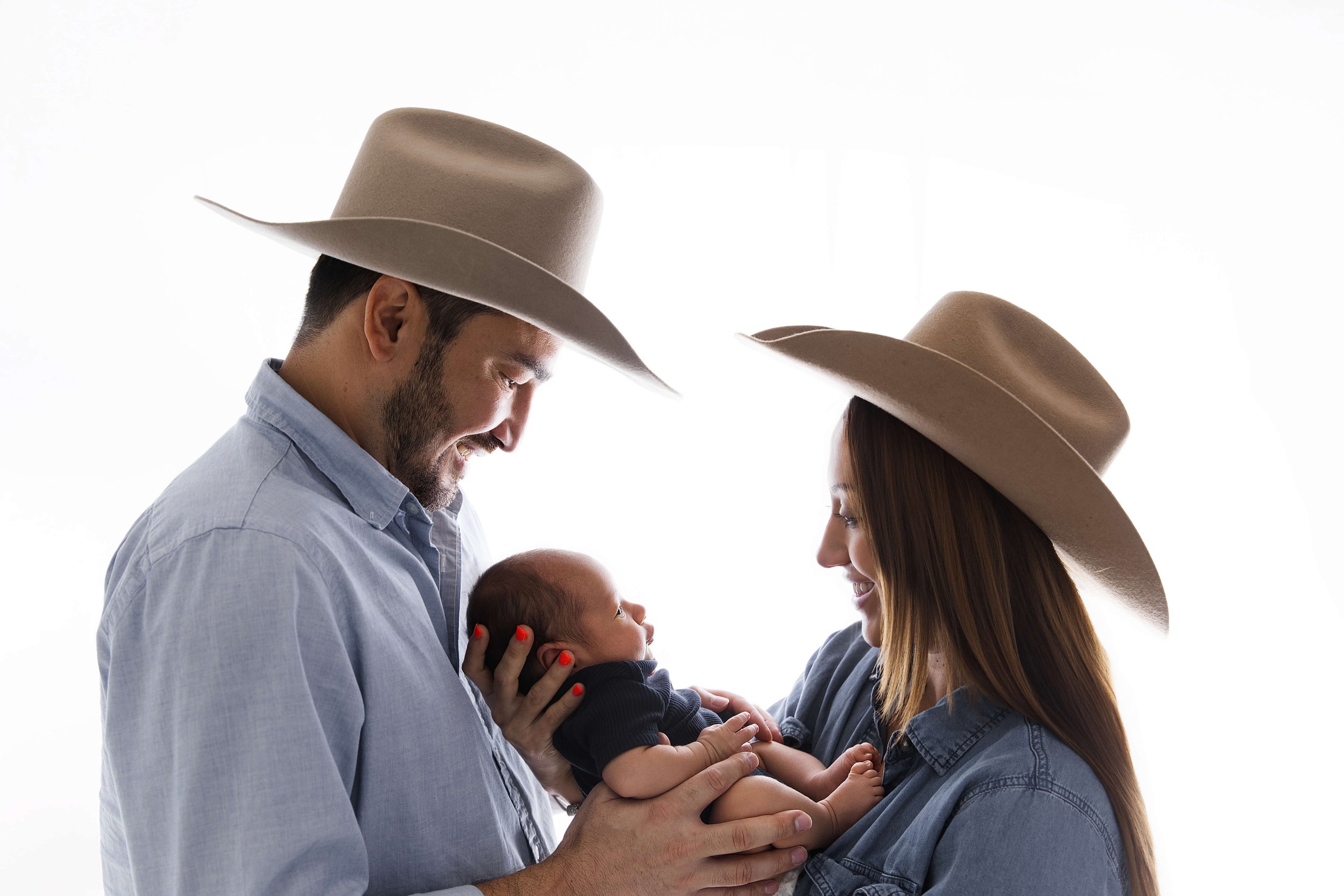 Parents wearing cowboy hats with newborn