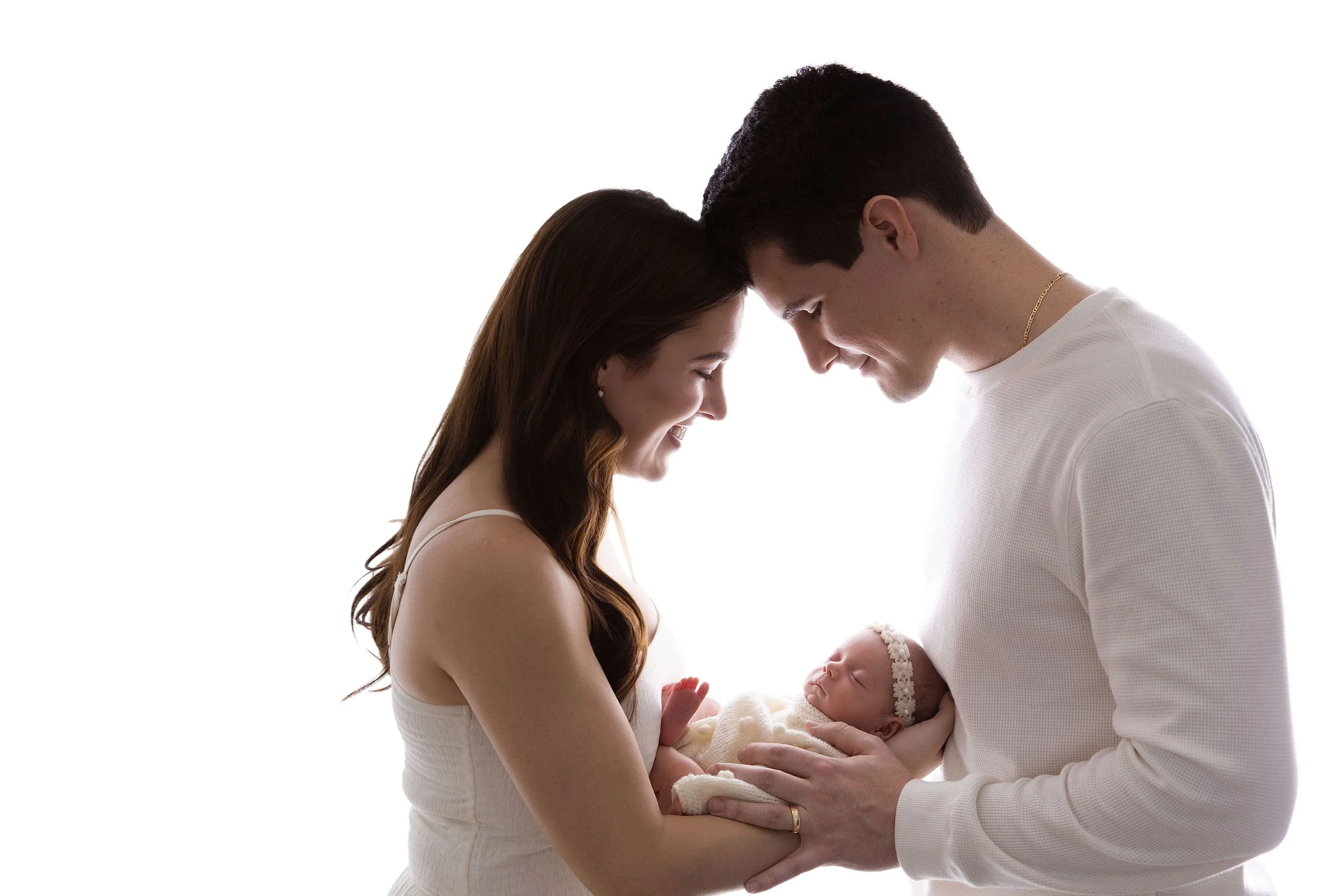 Backlit lifestyle newborn photo of a mother and father holding their baby during a Frisco TX newborn photography session